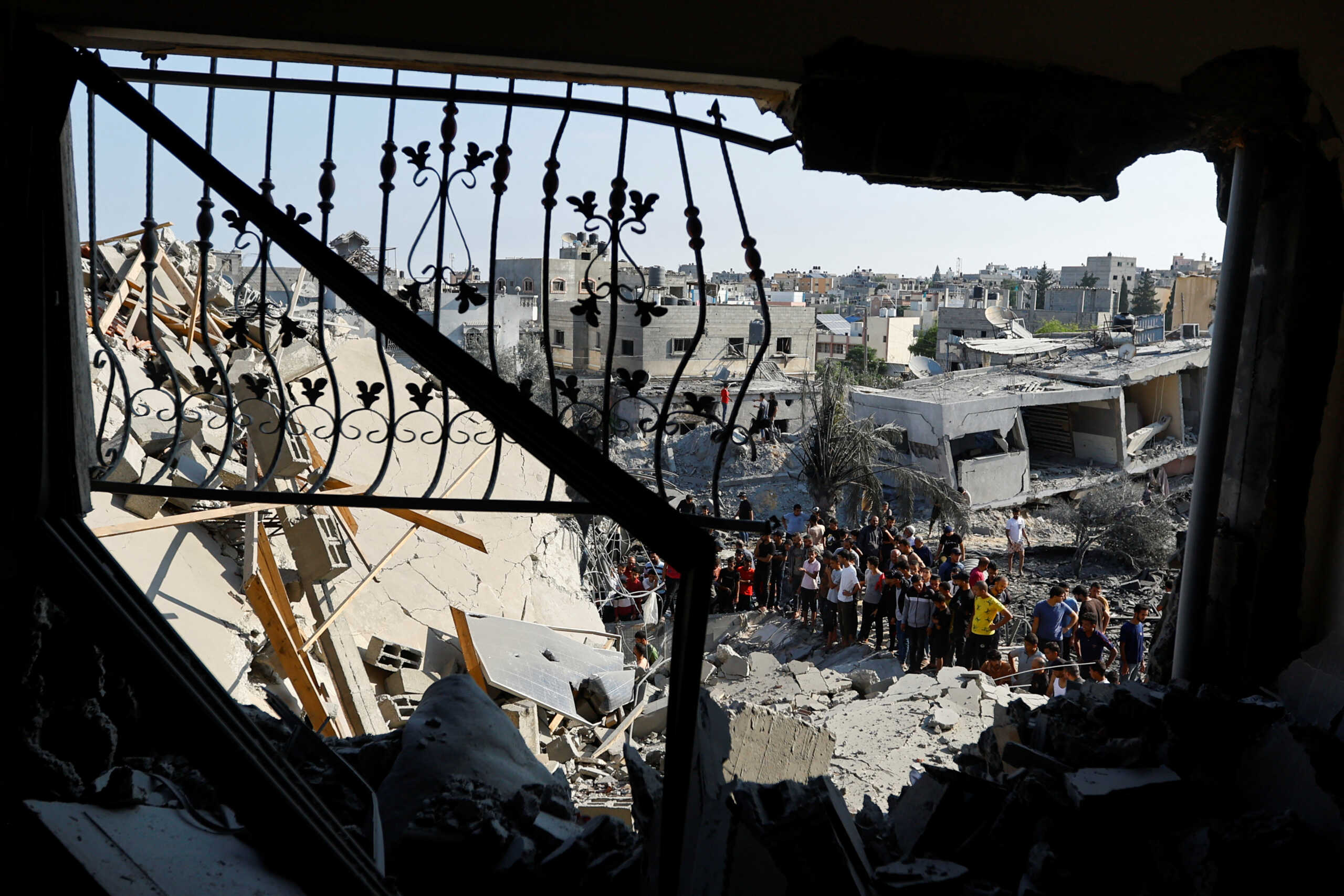 Palestinians gather near the rubble in the aftermath of Israeli strikes, in Khan Younis in the southern Gaza Strip, October 14, 2023.  REUTERS