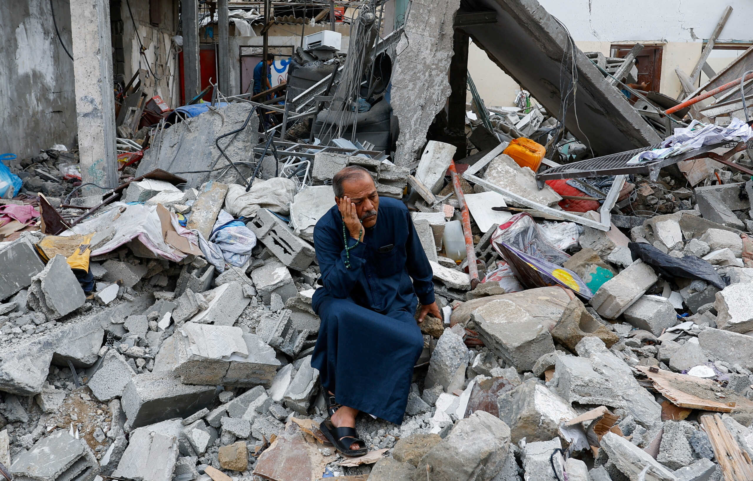 A Palestinian sits on the rubble of a building destroyed in Israeli strikes, in Rafah in the southern Gaza Strip October 9, 2023. REUTERS