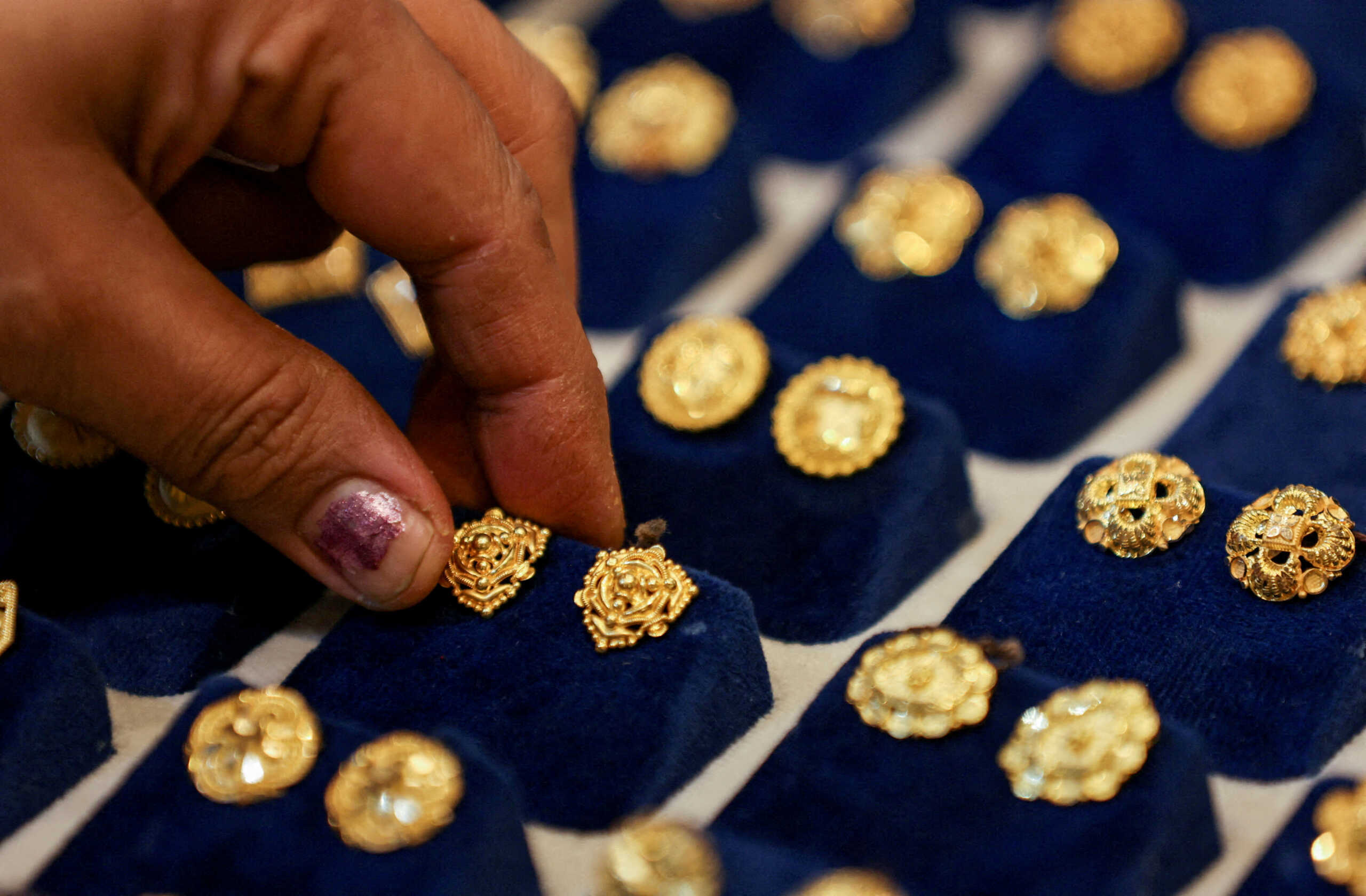 FILE PHOTO: FILE PHOTO: A woman picks a gold earring at a jewellery shop in the old quarters of Delhi, India, May 24, 2023. REUTERS