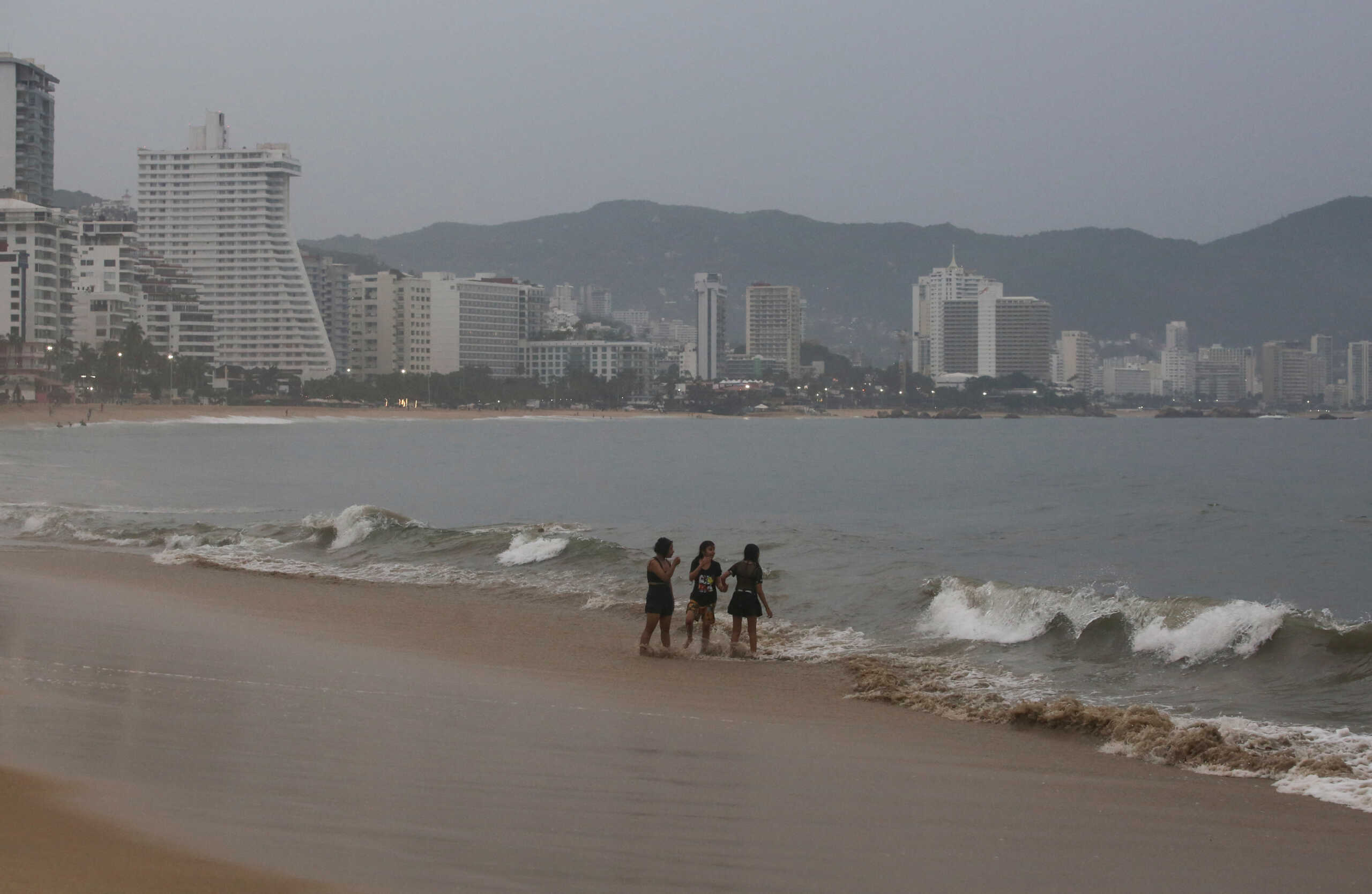 People stand on a beach as Hurricane Otis barrels towards Acapulco, Mexico, October 24, 2023. REUTERS