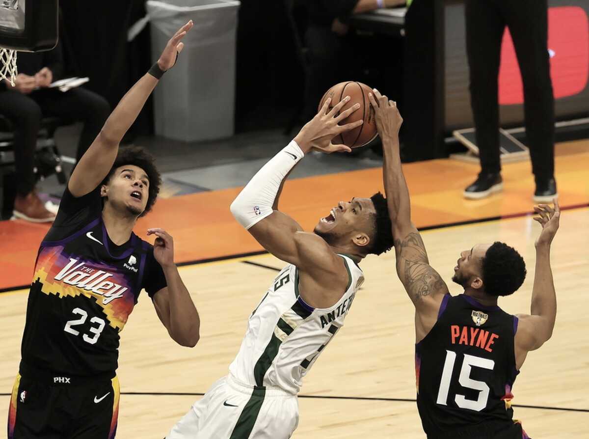 epa09332704 Milwaukee Bucks forward Giannis Antetokounmpo (C) is fouled as he shoots between Phoenix Suns Cameron Johnson (L) and Cameron Payne (R) in the first quarter of game two of the 2021 NBA Finals basketball playoff series between Milwaukee Bucks and Phoenix Suns the at Phoenix Suns Arena in Phoenix, Arizona, USA, 08 July 2021.  EPA