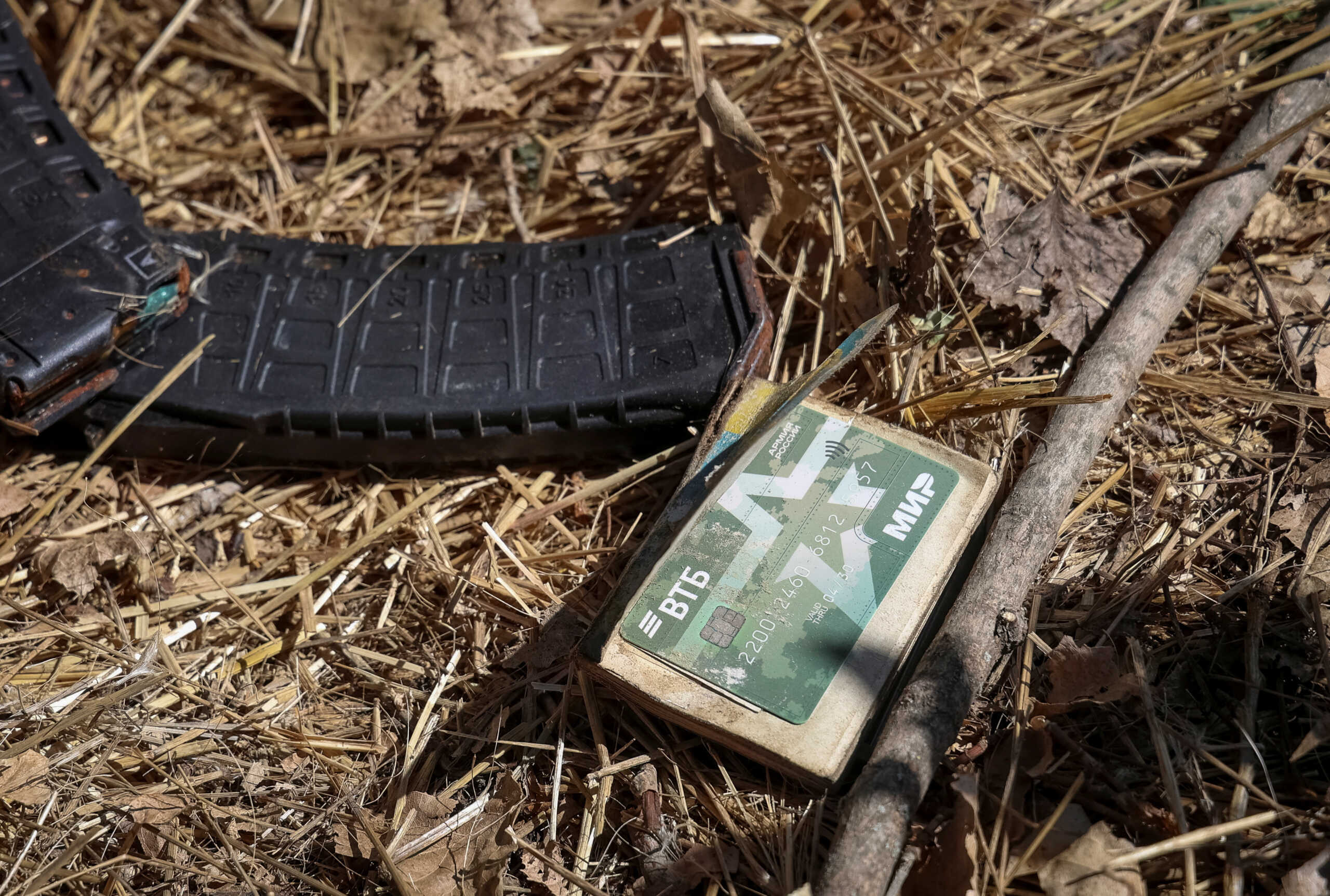 Assault rifle magazines with cartridges and a bank card with the inscription "Russian Army, World" are seen near a body of a dead Russian soldier, amid Russia's attack on Ukraine, in the village of Blahodatne in Donetsk Region Ukraine September 8, 2023. REUTERS