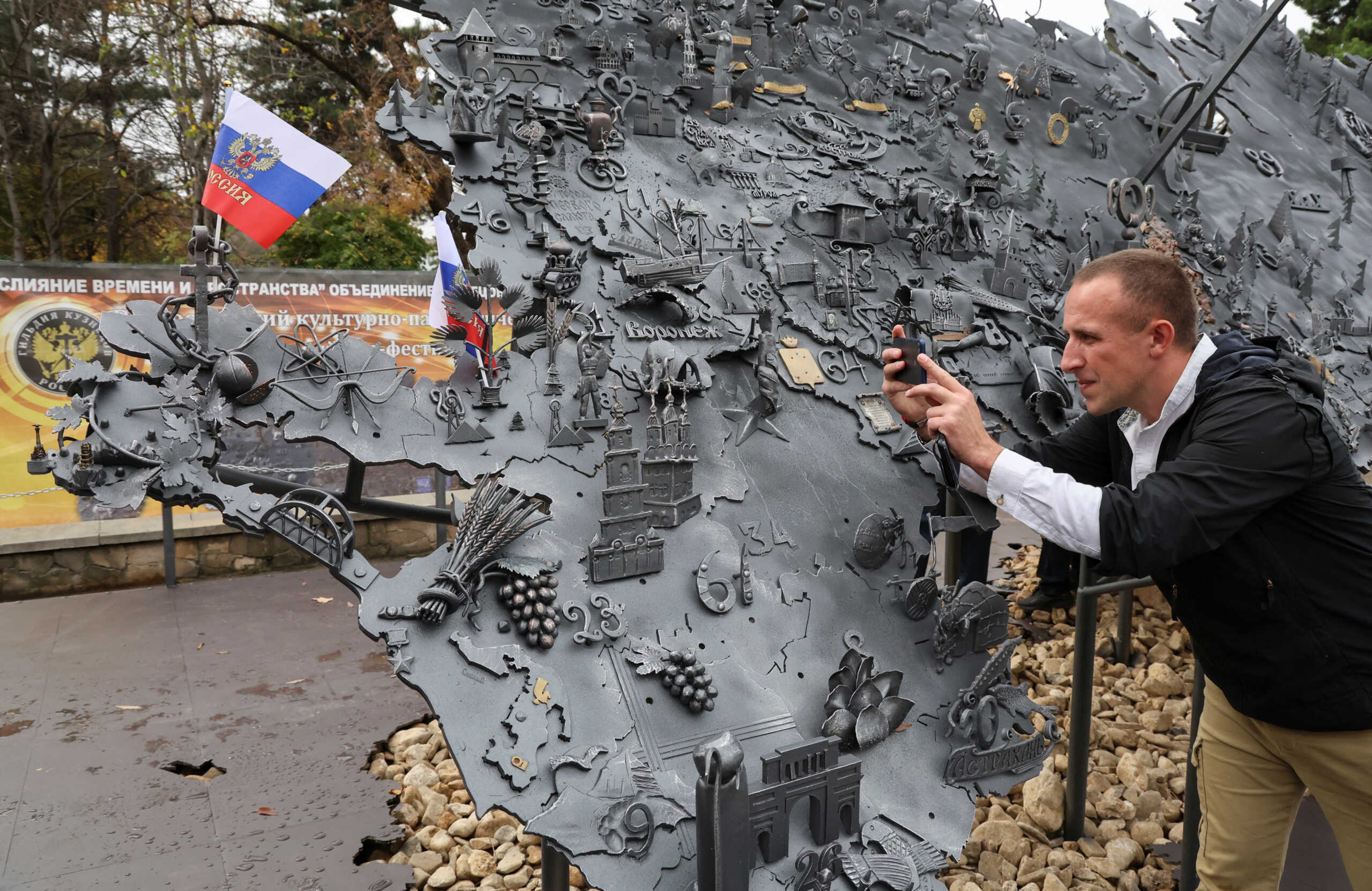 A man takes a picture of an installation depicting a map of Russia with Russian-controlled regions of Ukraine on National Unity Day, in Simferopol, Crimea, November 4, 2023. REUTERS