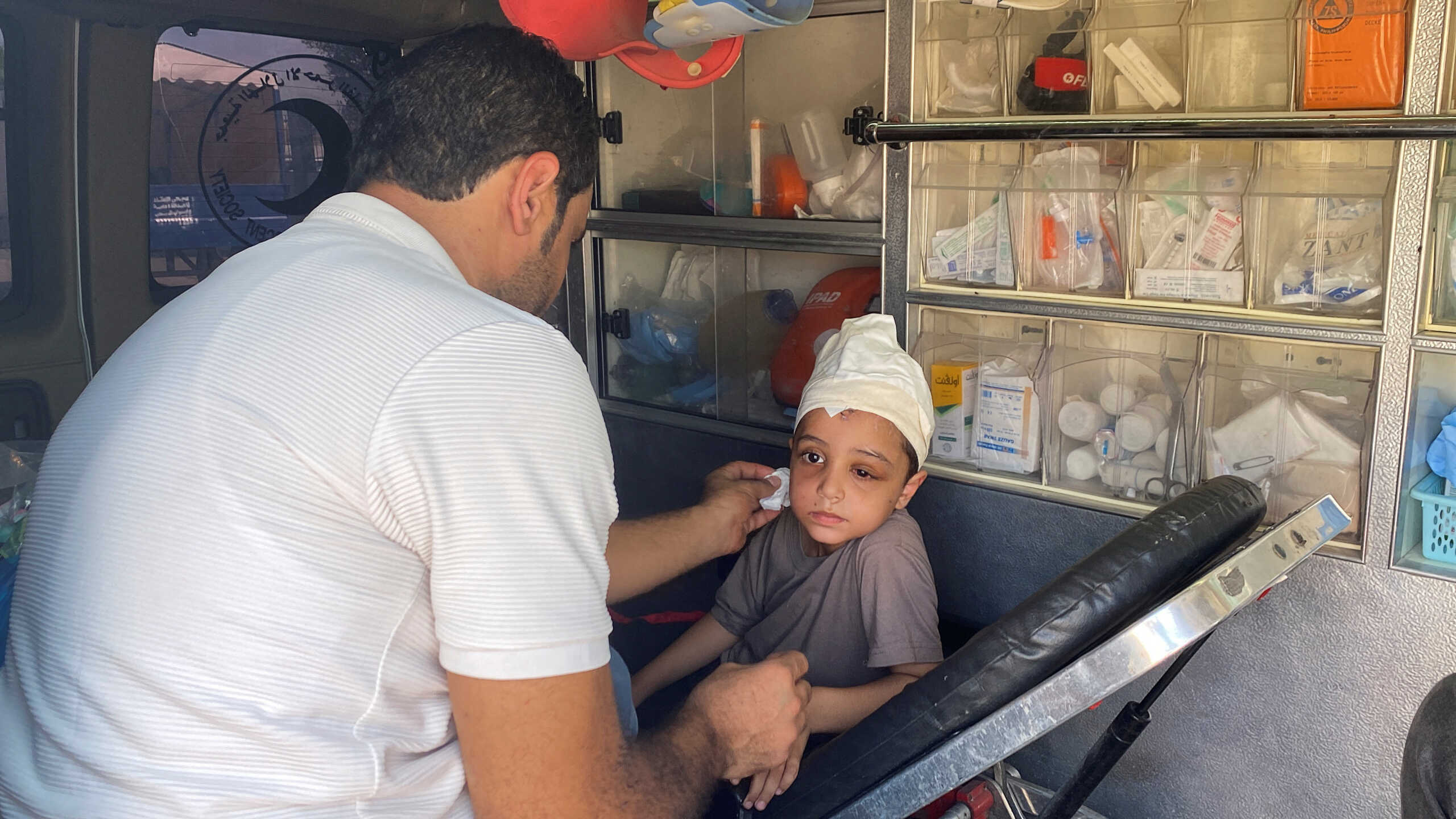 Palestinian boy Ameer Joma, who was injured in an Israeli strike, sits with his father in an ambulance as they wait to be transported for treatment in an Egyptian hospital, at the Rafah border crossing in the southern Gaza Strip, November 1, 2023. REUTERS