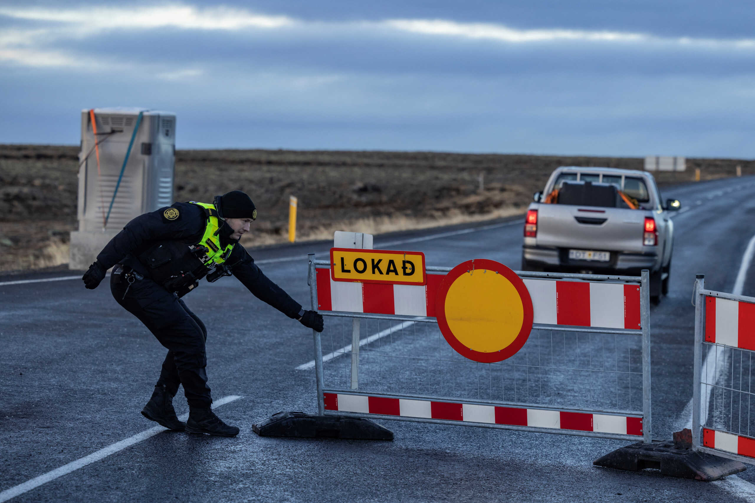 A police officer pulls a barrier to block the road leading to the fishing town of Grindavik, which was evacuated due to volcanic activity, in Iceland November 16, 2023. REUTERS