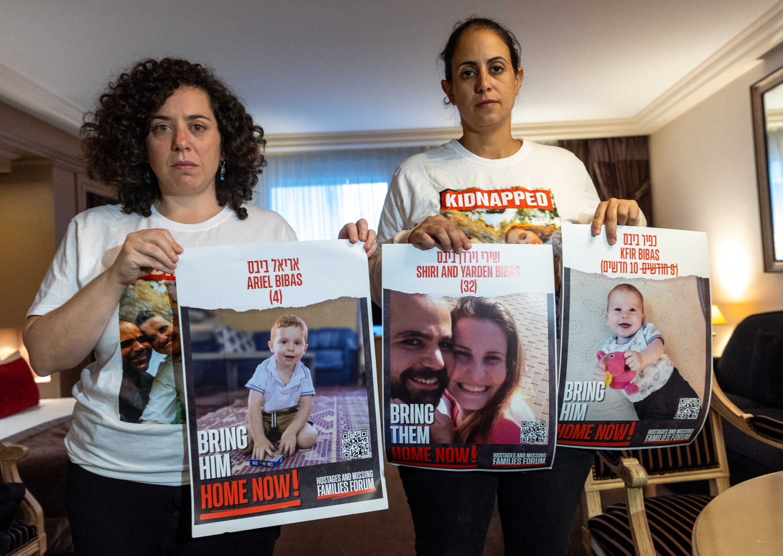 Ofri Bibas Levy, whose brother Yarden (34) was taken hostage with his wife Shiri (32) and 2 children Kfir (10 months) and Ariel (4),  holds with her friend Tal Ulus pictures of them during an interview with Reuters, as the conflict between Israel and the Palestinian Islamist group Hamas continues, in Geneva, Switzerland, November 13, 2023. REUTERS