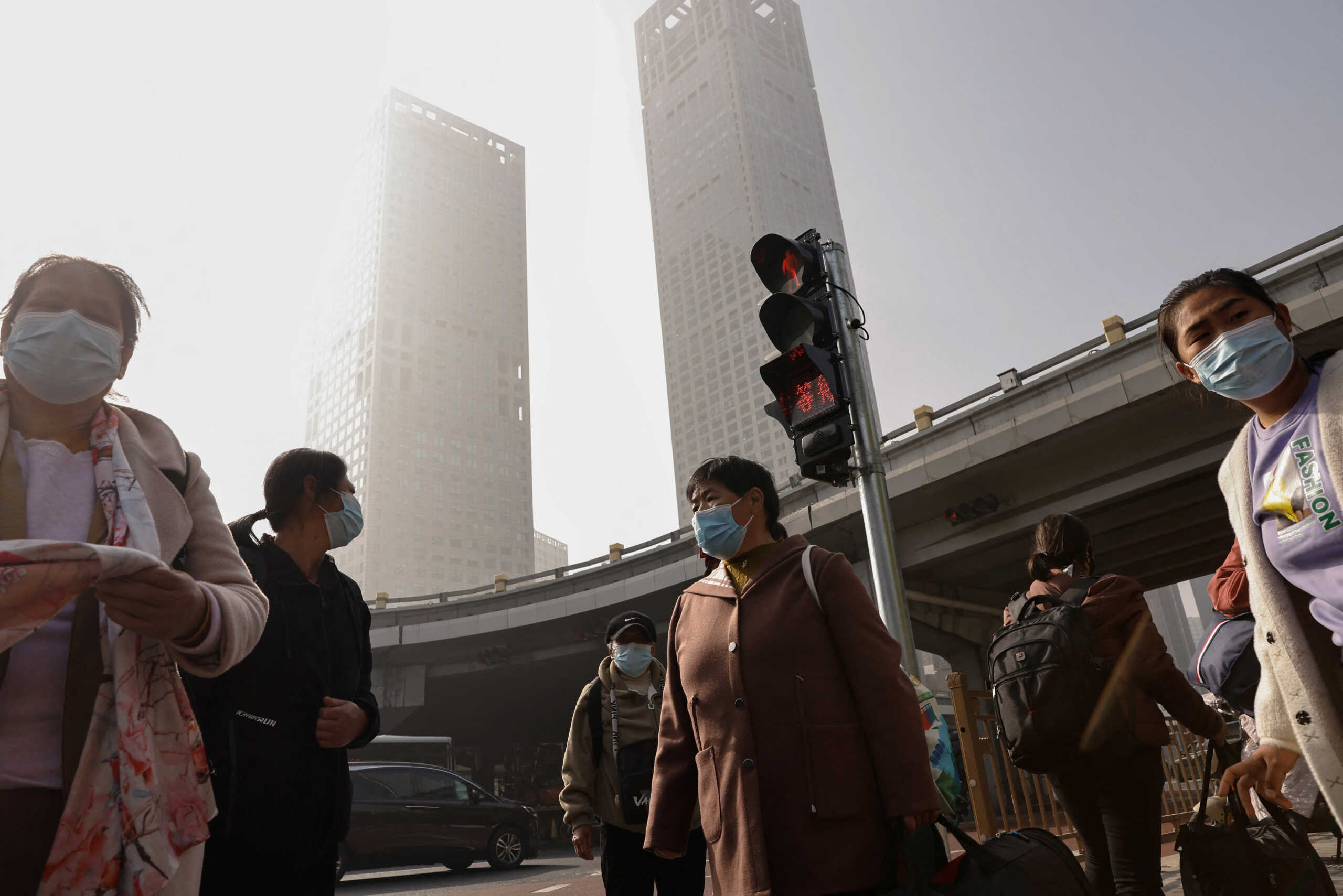 People wearing face masks wait at an intersection in Beijing's Central Business District (CBD), as the city is shrouded in smog, in China November 1, 2023. REUTER