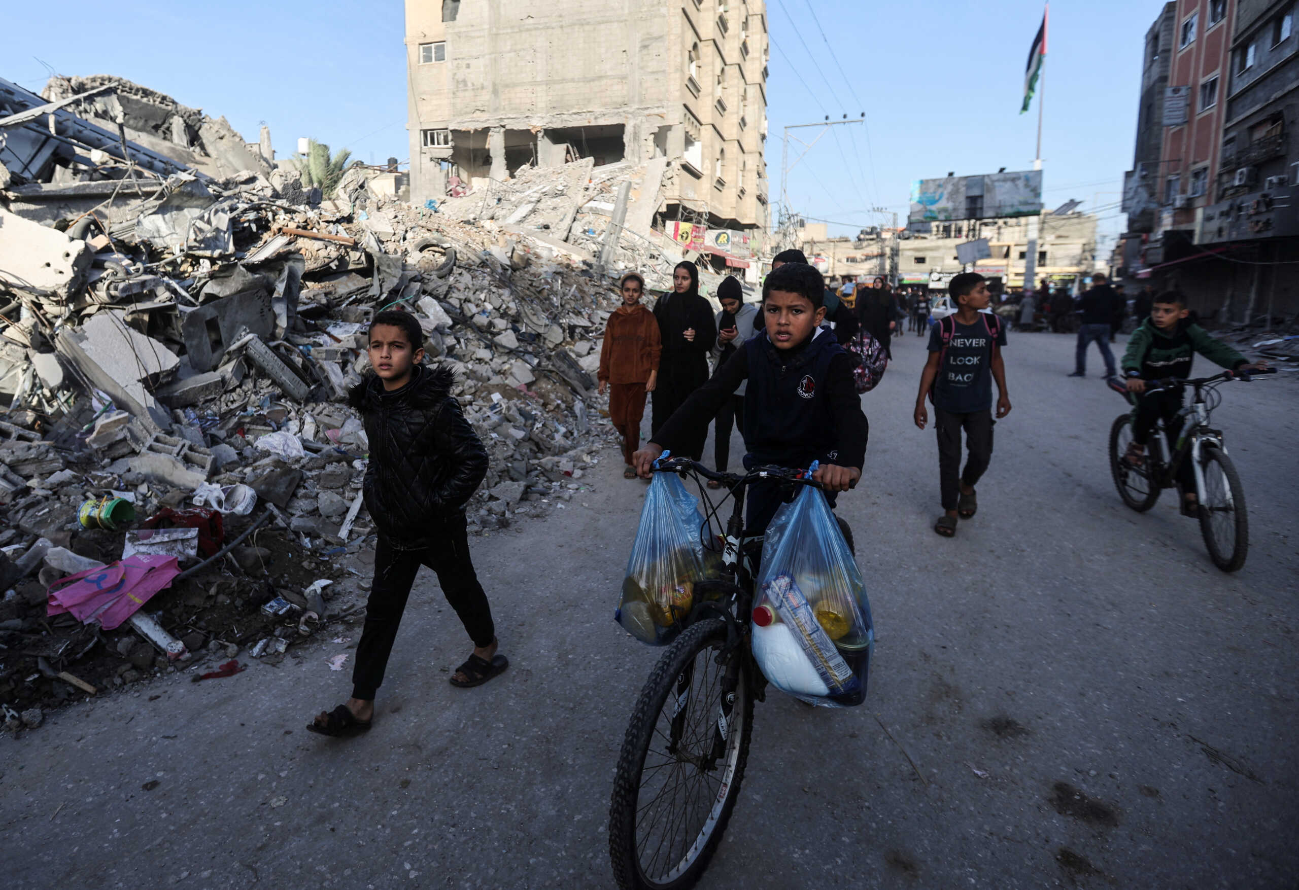 Displaced Palestinian children ride bicycles and walk on a street, during a temporary truce between Hamas and Israel, in Khan Younis in the southern Gaza Strip, November 24, 2023. REUTERS