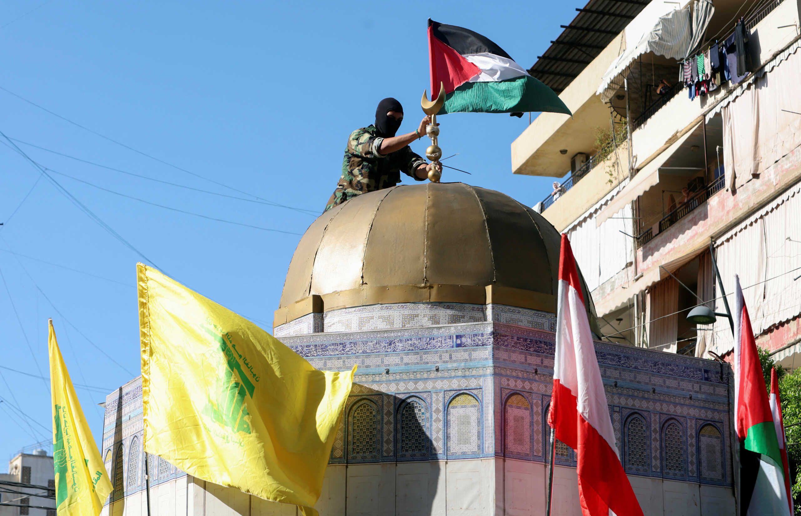 A Hezbollah member puts a Palestinan flag atop of a replica of the Dome of the Rock as people gather to commemorate the annual Hezbollah Martyrs' Day and to express solidarity with the Palestinians in Gaza amid the ongoing conflict between Israel and Hamas, in Sidon, Lebanon November 10, 2023. REUTERS