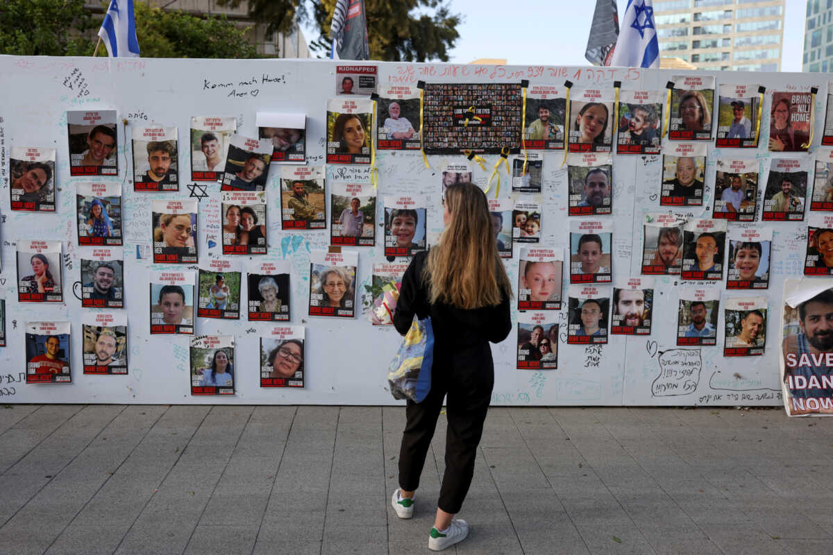 A woman looks at an installation which shows the pictures of hostages taken by Palestinian Islamist group Hamas following a deadly infiltration of Israel by Hamas gunmen from the Gaza Strip on October 7, before some of them are due to be released as part of a deal between Israel and Hamas to free hostages held in Gaza in exchange for the release of Palestinian prisoners, in Tel Aviv, Israel, November 24, 2023. REUTERS