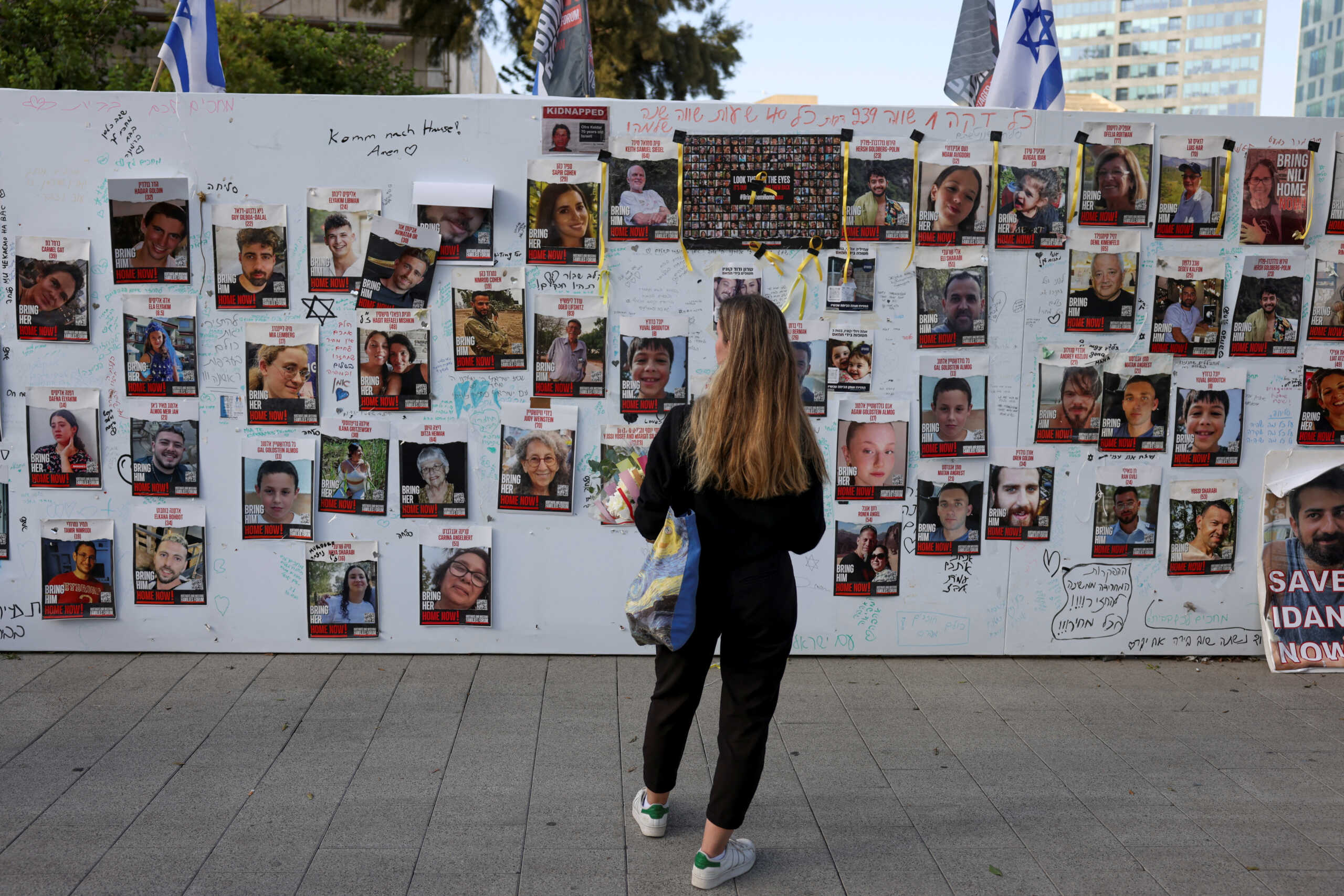 A woman looks at an installation which shows the pictures of hostages taken by Palestinian Islamist group Hamas following a deadly infiltration of Israel by Hamas gunmen from the Gaza Strip on October 7, before some of them are due to be released as part of a deal between Israel and Hamas to free hostages held in Gaza in exchange for the release of Palestinian prisoners, in Tel Aviv, Israel, November 24, 2023. REUTERS
