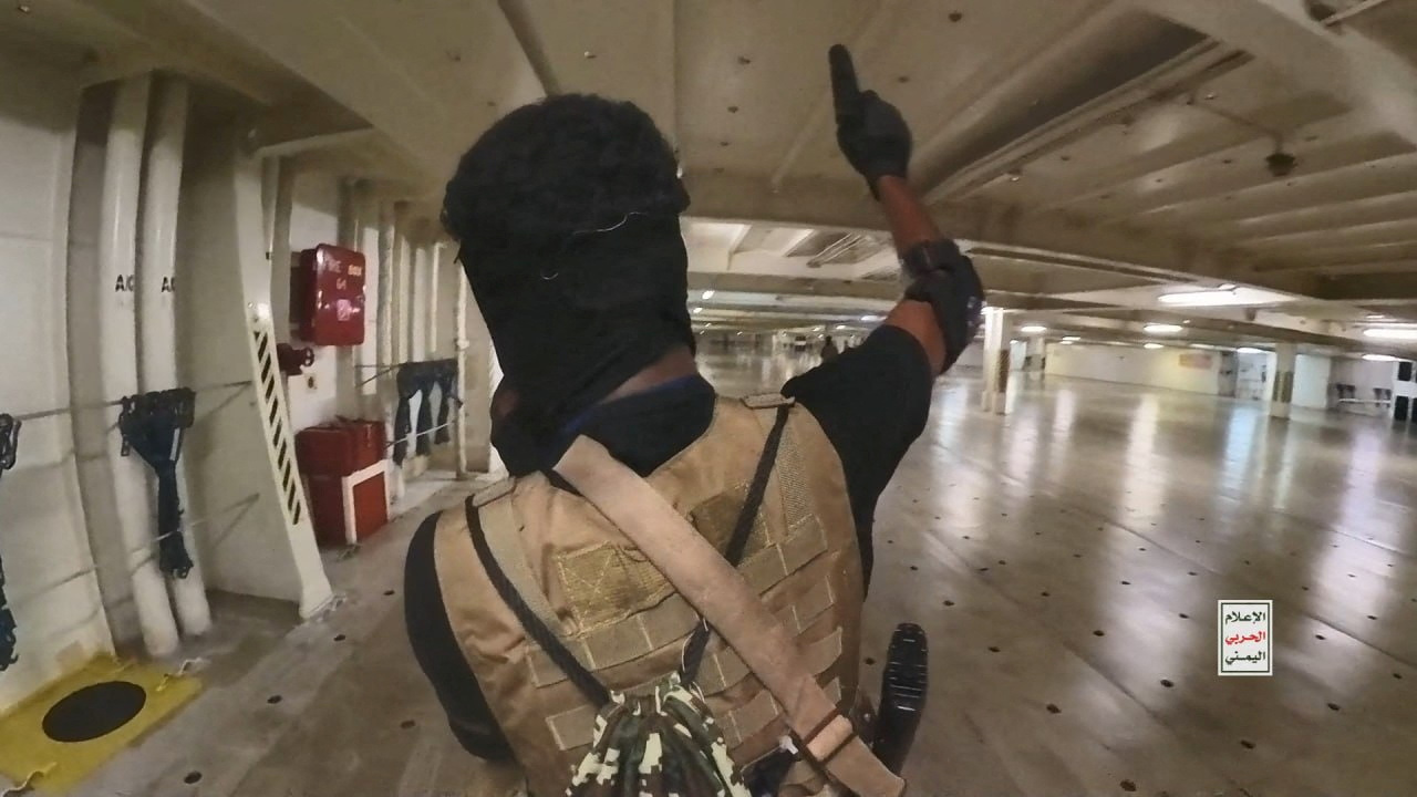 A Houthi fighter holds up a pistol in the cargo area of the Galaxy Leader cargo ship in the Red Sea in this photo released November 20, 2023. Houthi Military Media
