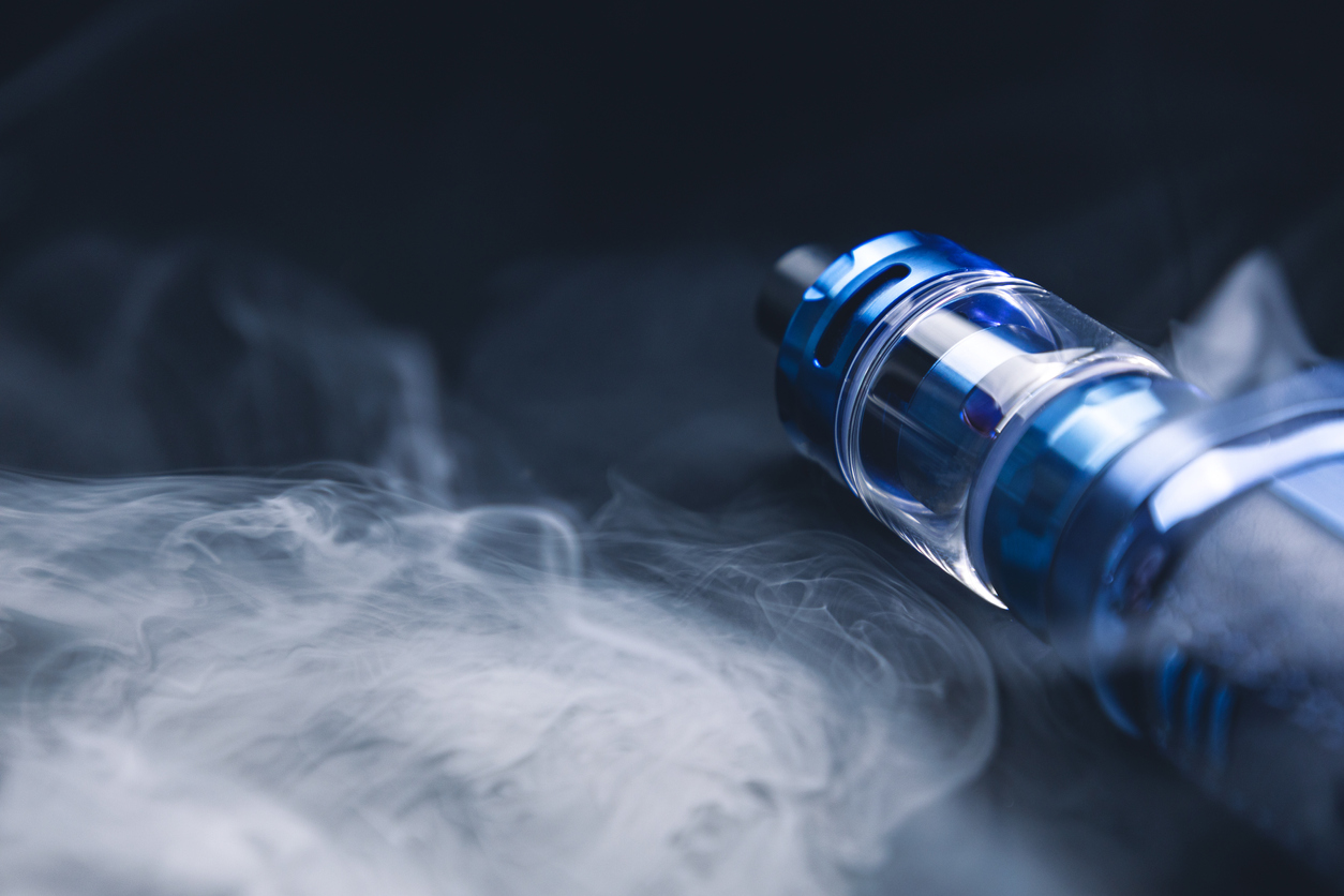 Vape on a black background in smoke, an electronic cigarette for smoking nicotine, a lot of steam from a cigarette