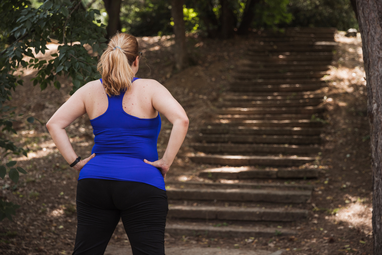Woman holding hands on hips when observing stairs in a park that she was about to run on