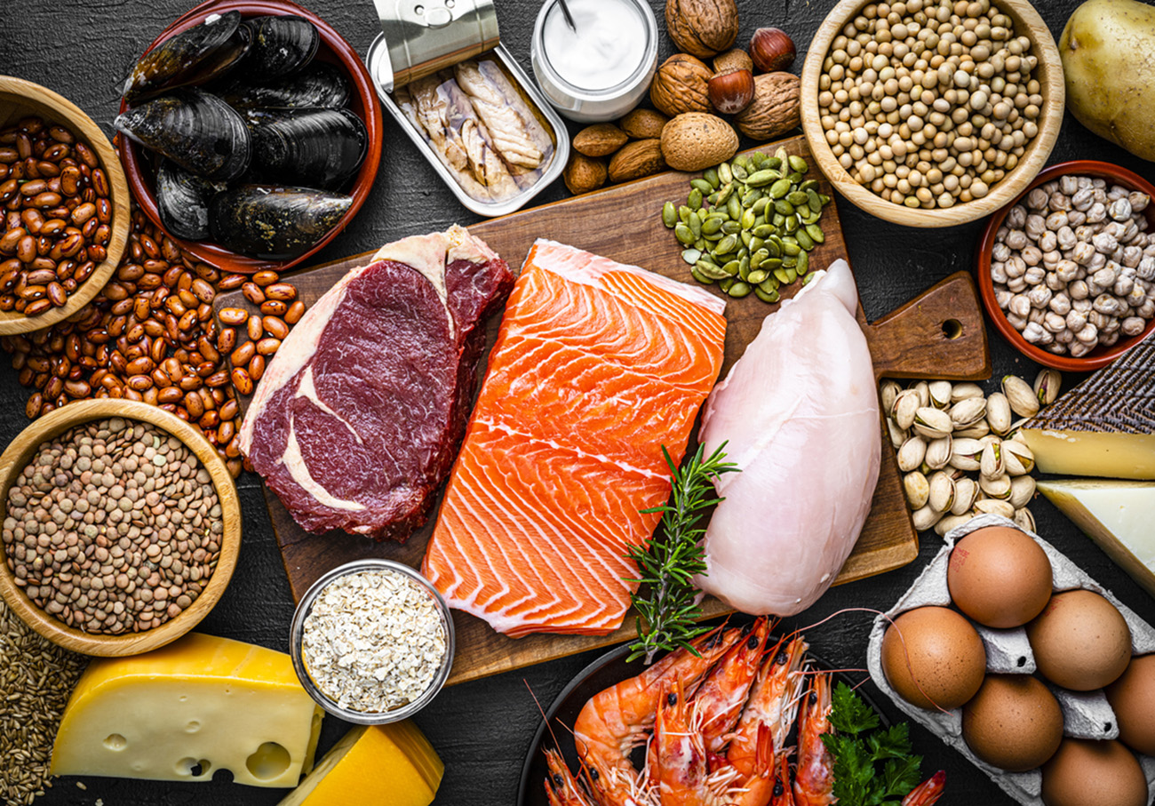 Overhead view of a large group of food with high content of healthy proteins. The composition includes salmon beef fillet, chicken breast, eggs, yogurt, mussels, chick peas, pistachios, cheese, brown lentild, beans, shrimps, canned tuna, pumpkin seeds, soybeans among others. High resolution 42Mp studio digital capture taken with SONY A7rII and Zeiss Batis 40mm F2.0 CF lens