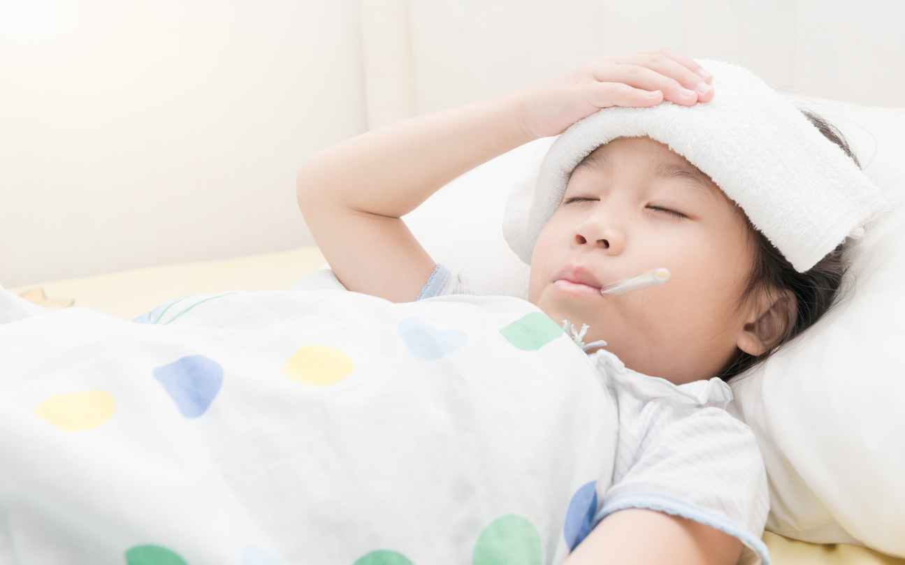 Sick child girl lying in bed and thermometer in mouth