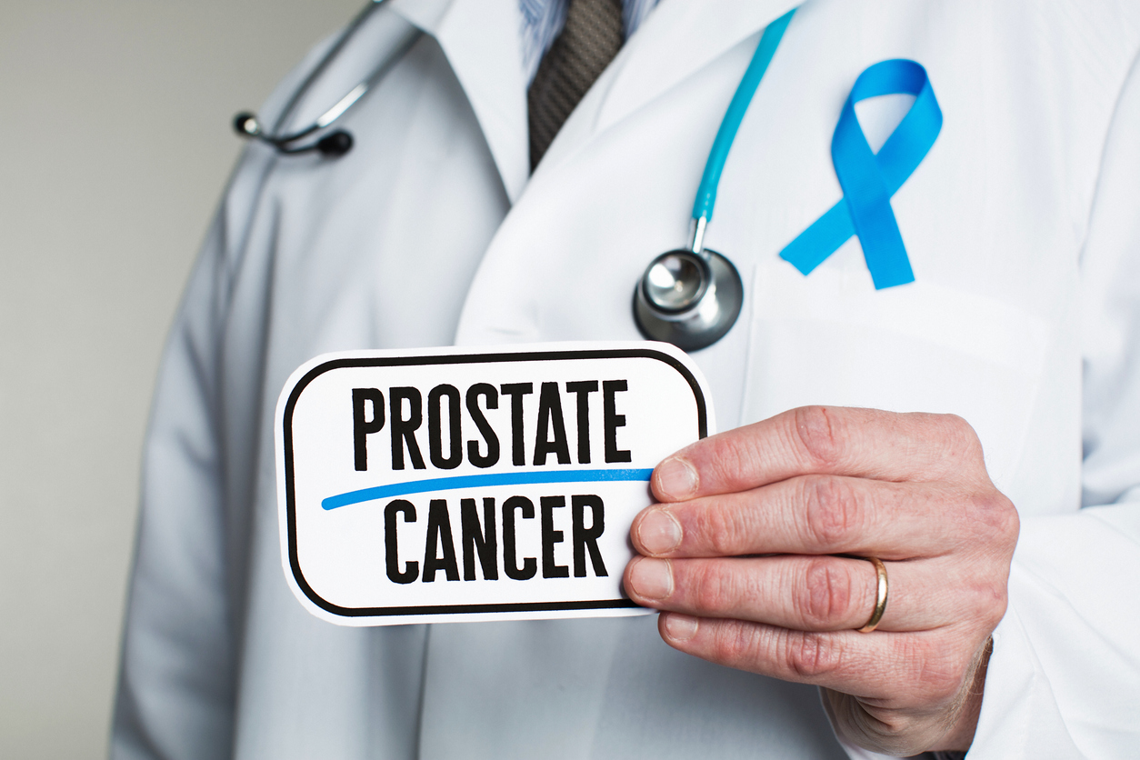 Doctor with stethoscope in white lab coat holding sign reading prostate cancer