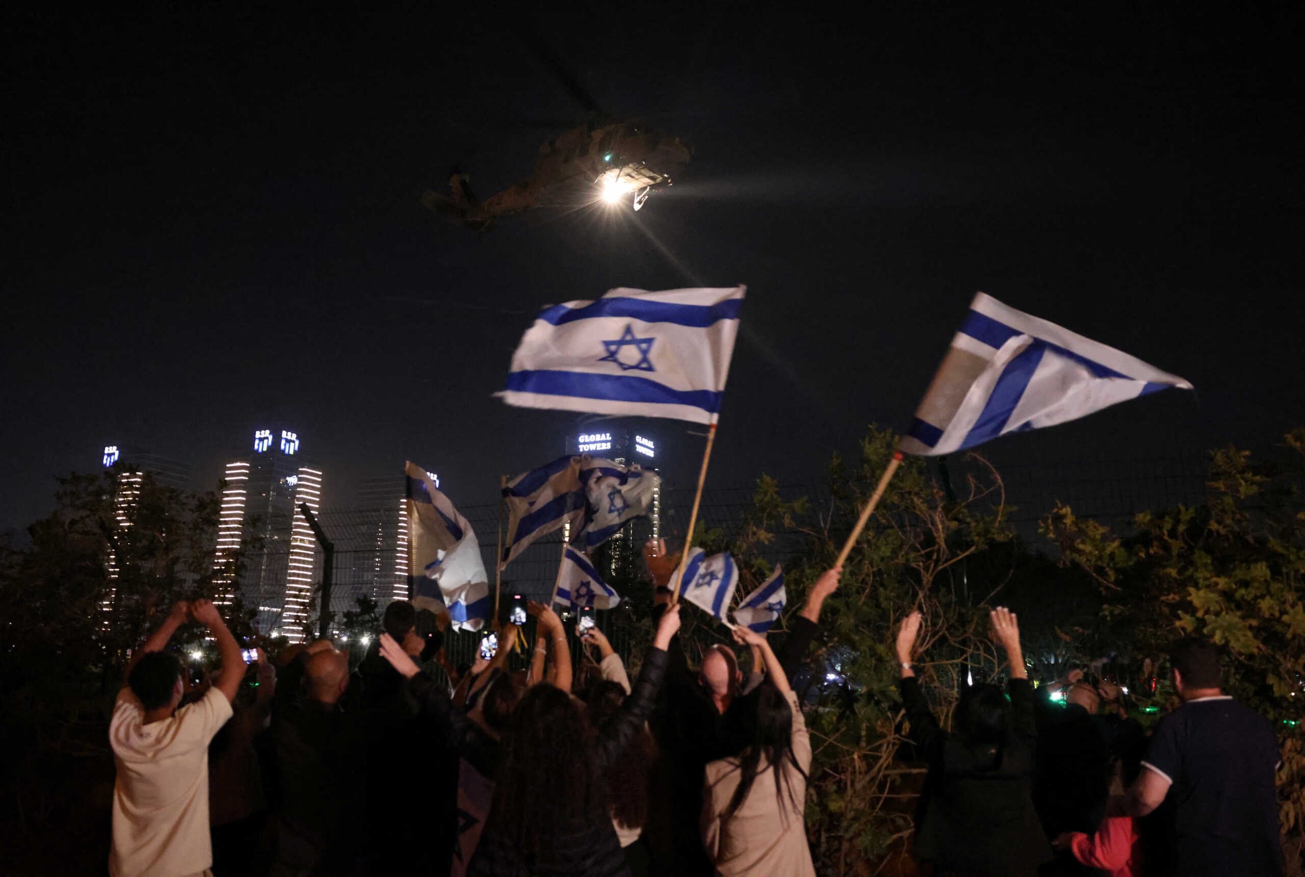 People wave Israeli flags as helicopter carrying hostages released as part of a deal between Israel and Palestinian Islamist group Hamas arrives at Schneider Children's Medical Center in Petah Tikva, Israel, November 24, 2023. REUTERS