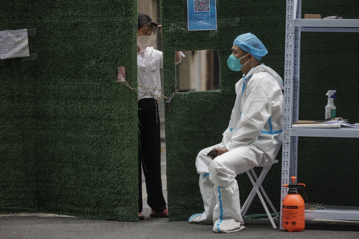 epa09989588 A woman still in quarantine watches people passing outside trough a barrier, while a security man guards the gate, on the first day of easing of COVID-19 restrictions, in Shanghai, China, 01 June 2022. The Shanghai Government lifted most COVID-19 restrictions on 01 June. The majority of Shanghai's 25-million-strong population was able to leave their compounds freely without using any passes, except those living in medium and high-risk areas. There are still 190,000 people under lockdown, as well as 450,000 in control zones.  EPA