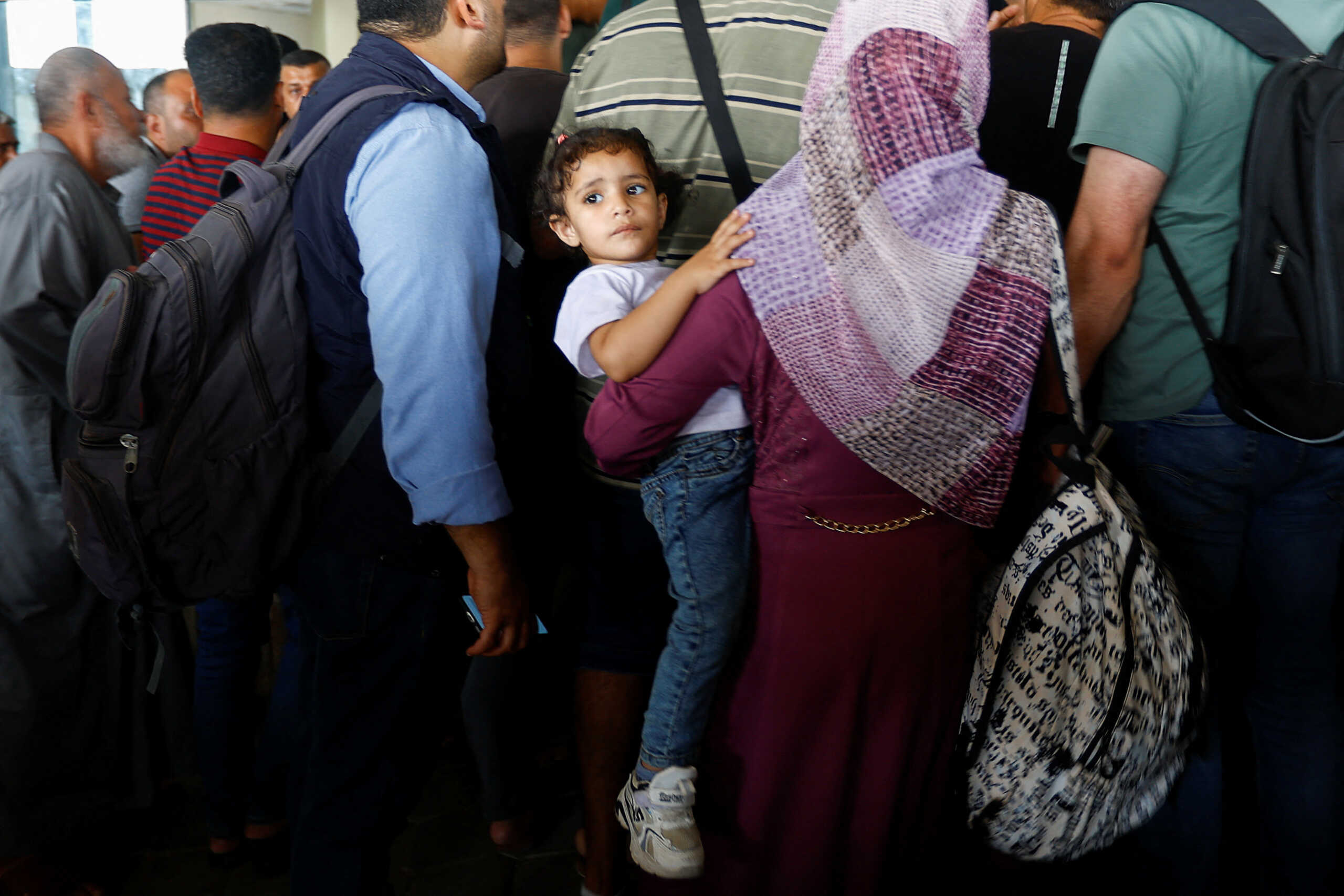 A woman holds a child, as Palestinians with dual citizenship wait at the Rafah border crossing with Egypt, in the hope of getting permission to leave Gaza, amid the ongoing conflict between Israel and Palestinian Islamist group Hamas, in Rafah in the southern Gaza Strip, November 1, 2023. REUTERS