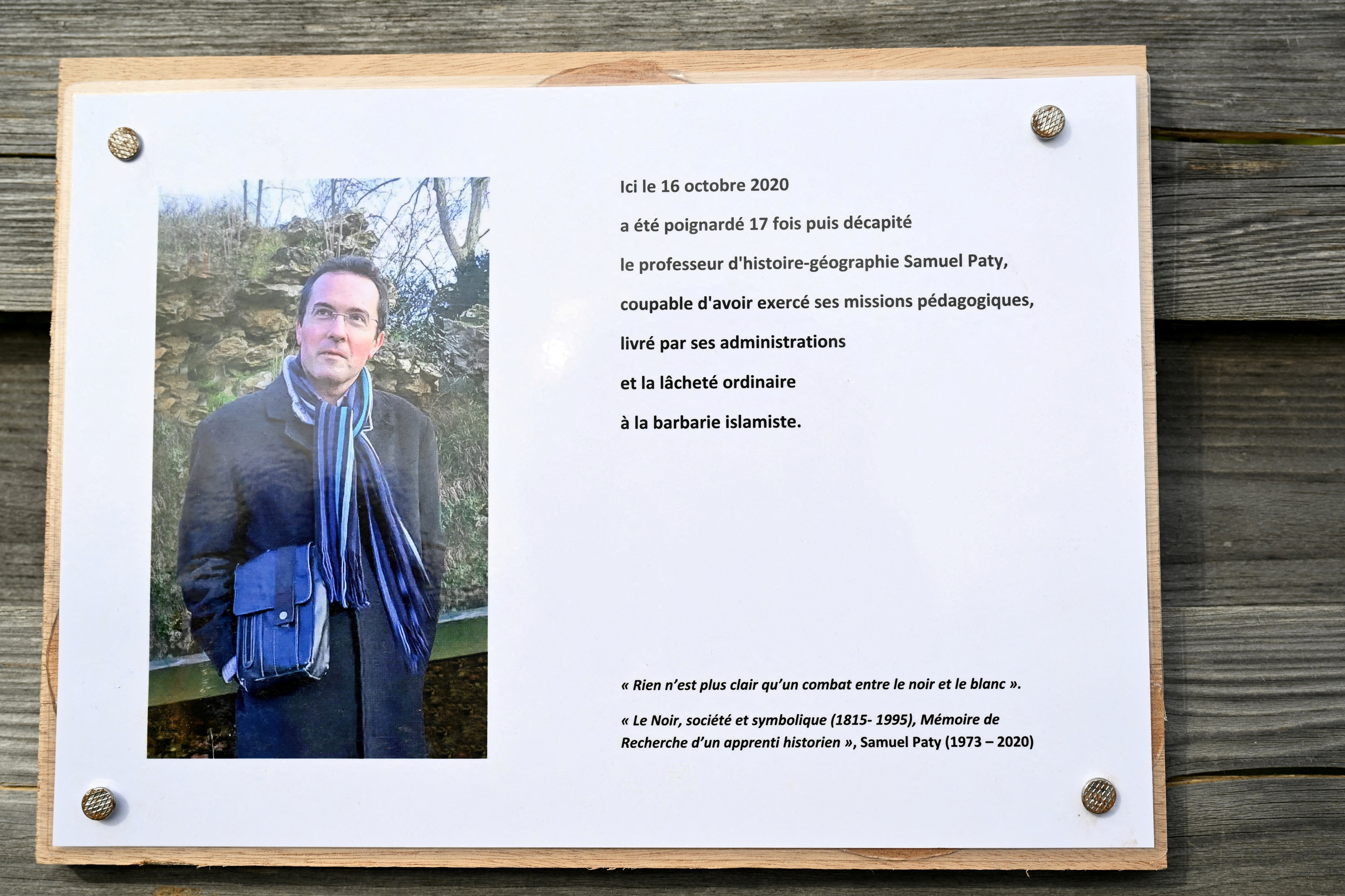 FILE PHOTO: A photograph taken on October 16, 2023 shows a commemorative plaque for slain teacher Samuel Paty (portrait) near the Bois d'Aulne school in Conflans-Sainte-Honorine, outside Paris.  BERTRAND GUAY