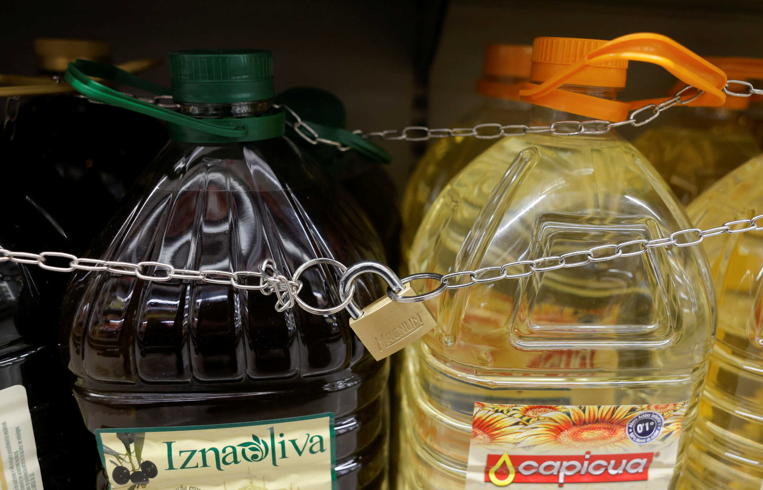 Olive and sunflower oil bottles are displayed for sale, protected by a padlock and a chain to prevent theft in a Tu Super Suma supermarket in Malaga, Spain, October 23, 2023. REUTERS