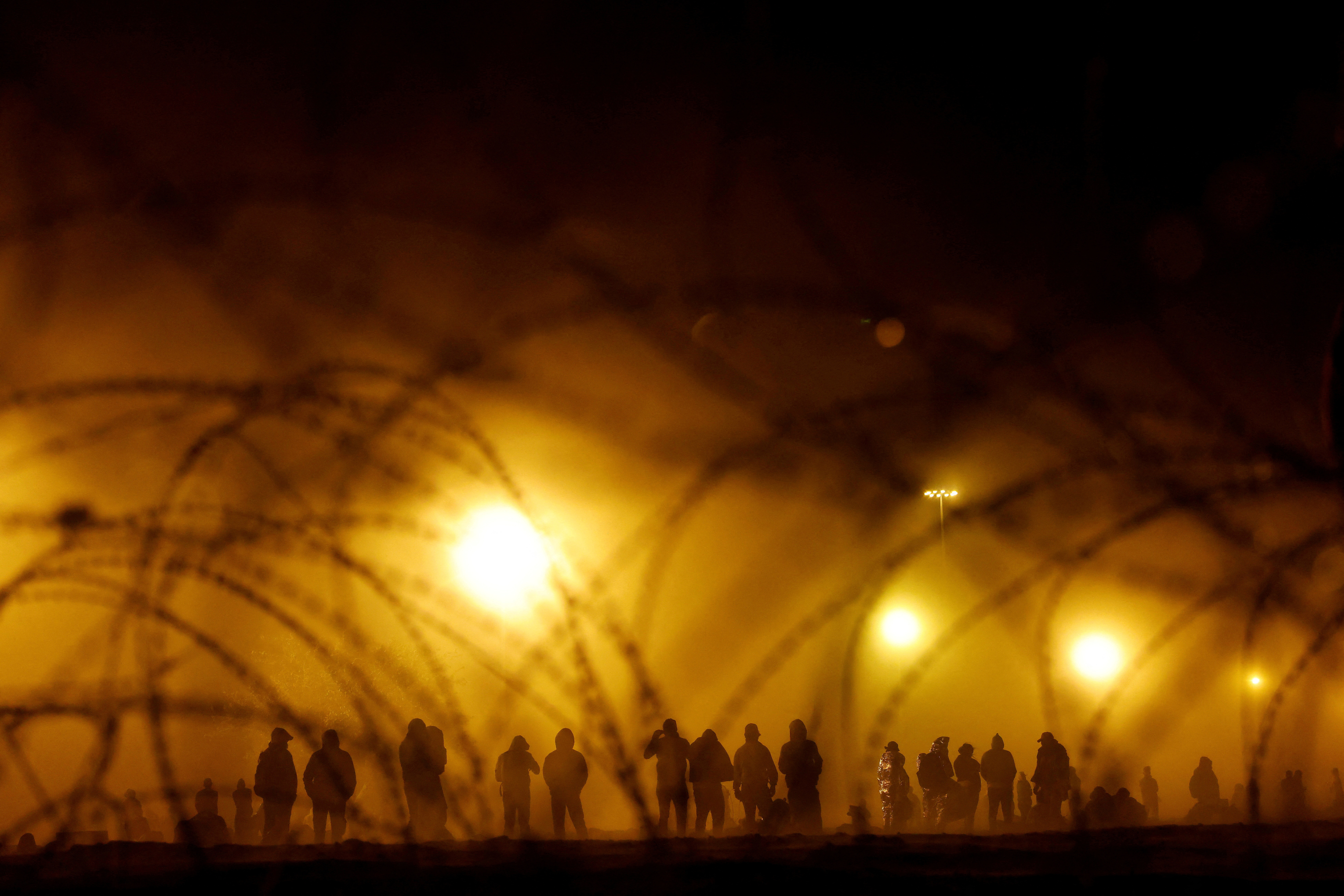 Migrants stand near the border wall during a sandstorm after having crossed the U.S.-Mexico border to turn themselves in to U.S. Border Patrol agents, as the country prepares to lift COVID-19 era Title 42 restrictions that have blocked migrants at the border from seeking asylum since 2020, in El Paso, Texas, U.S., May 10, 2023. Photographer Jose Luis Gonzalez spent much of 2023 documenting how migrants from around the world desperate for a better life seek to cross the border from Mexico into the United States. The migrants Gonzalez portrays have generally left everything behind. Many have traveled for months without a clear idea about what awaits them. "It is a daily occurrence at the border to see asylum-seeking migrants trying to cross into the United States, and yet, I am always amazed to learn the stories behind the people," said Gonzalez.         REUTERS