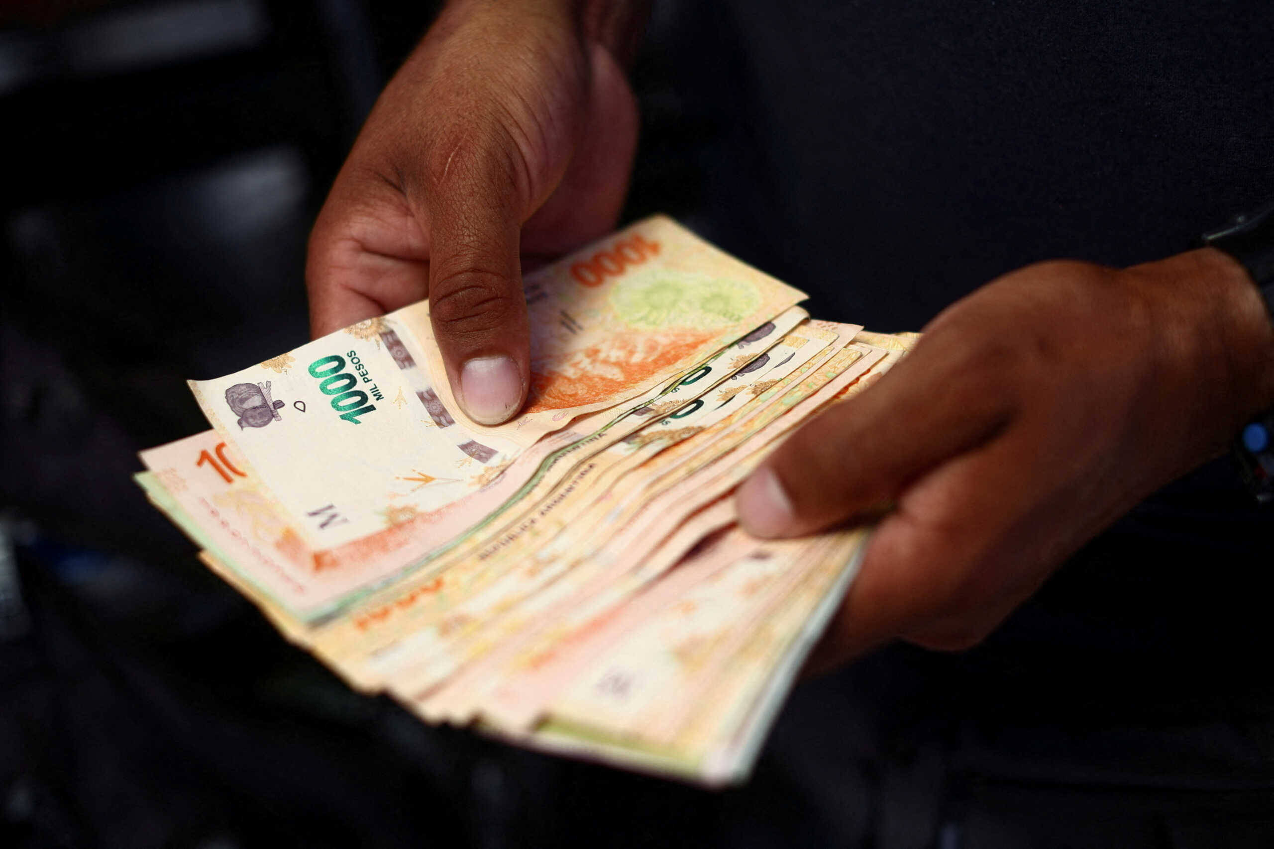 A street food vendor counts money in Buenos Aires, Argentina, December 12, 2023. REUTERS