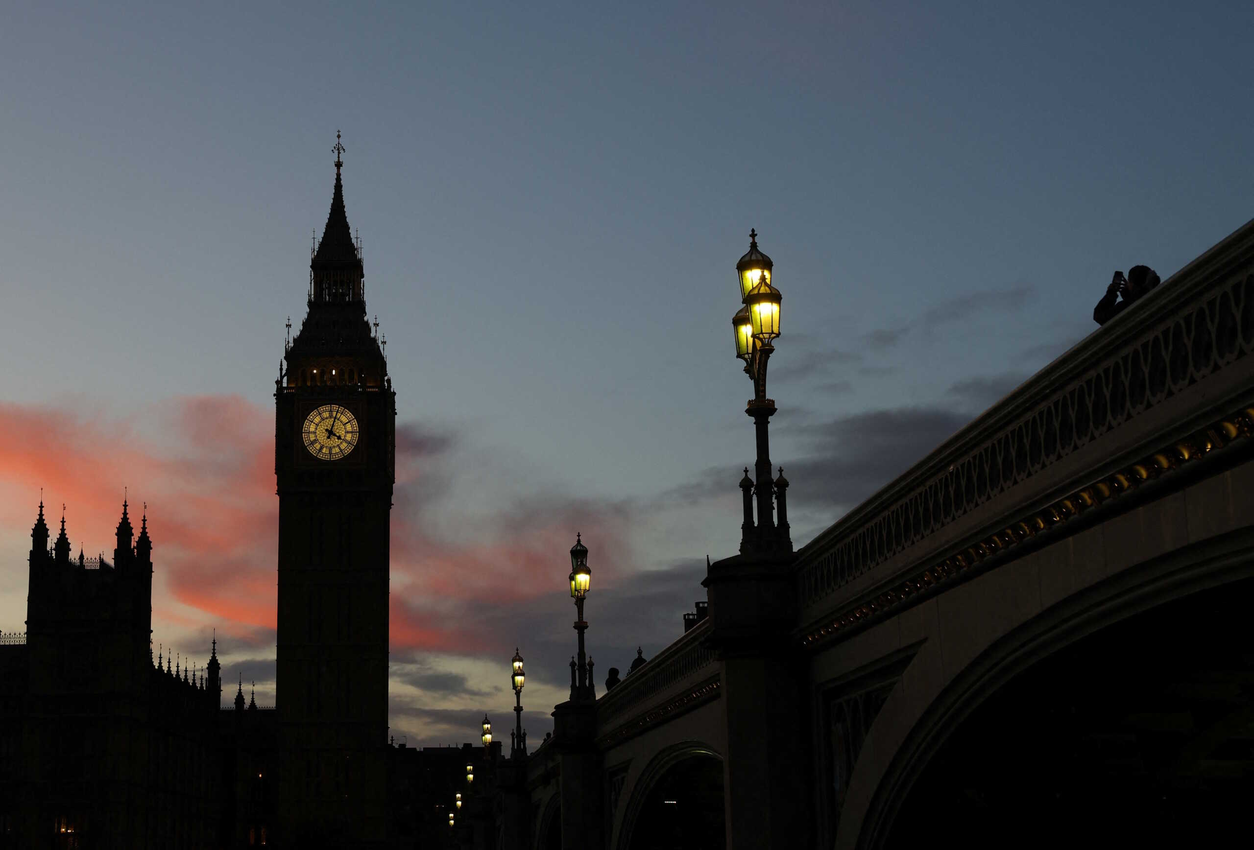 A person points a cellphone at the Elizabeth Tower, more commonly known as Big Ben, and the Houses of Parliament at dusk in London, Britain, December 12, 2023. REUTERS