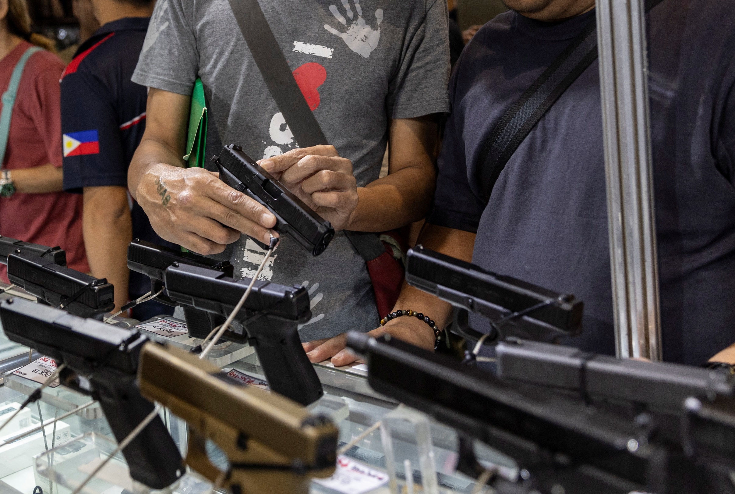 People look at pistols at a gun show in Pasay, Metro Manila, Philippines, December 7, 2023. REUTERS