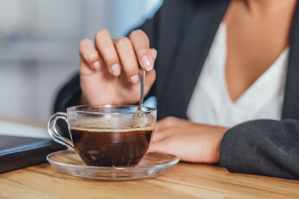 A wooden desktop with a morning black cup of coffee. Also, a notebook, diary, pen and document folder on the background, no one focuses on coffee