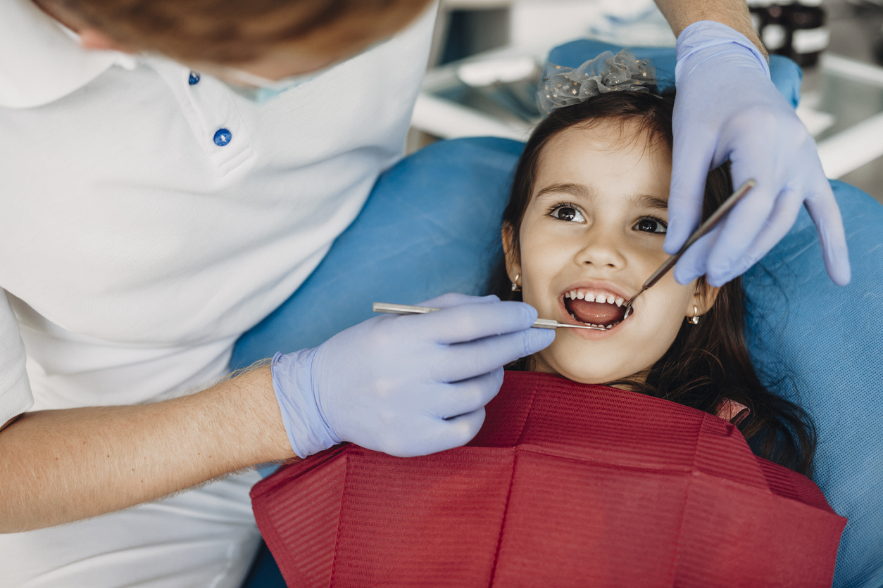 Close up of a cute little kid doing teeth surgery by a pediatric dentist.