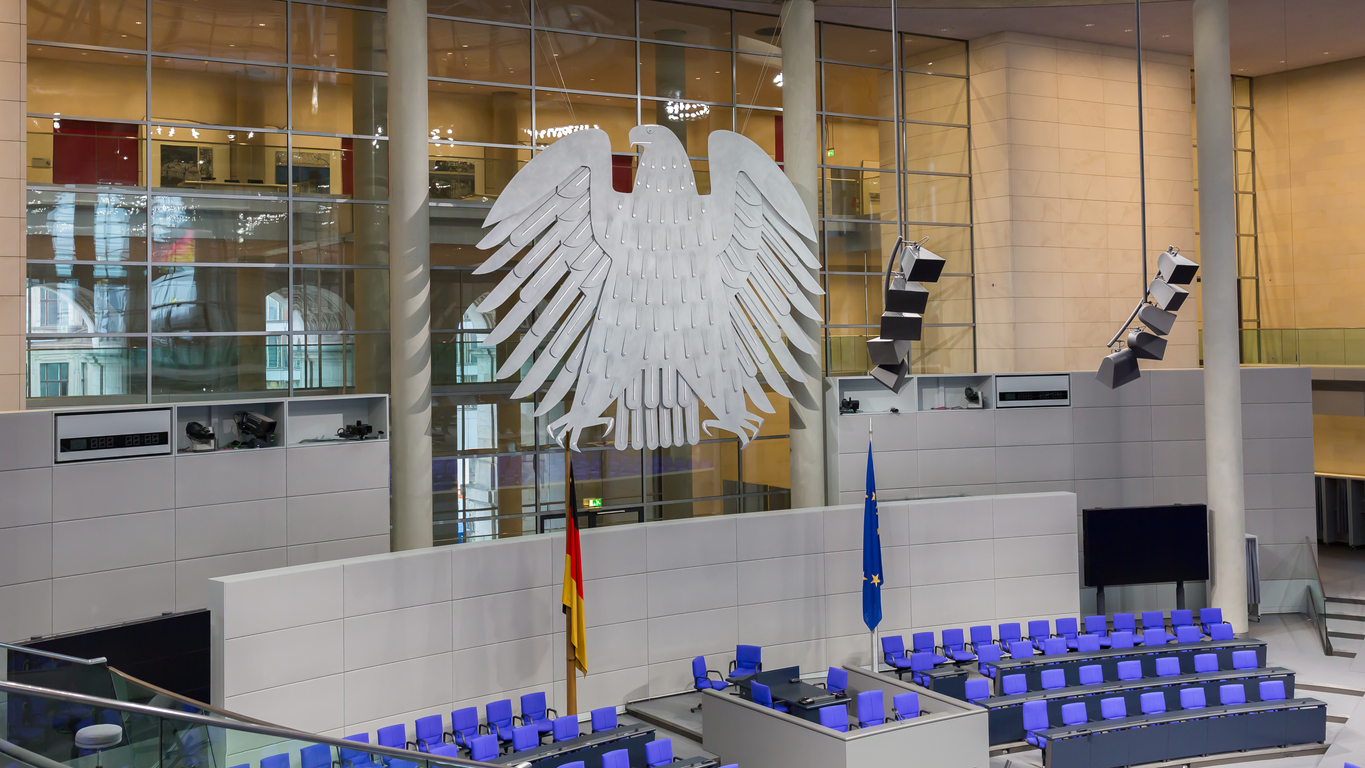 Berlin, Germany - Jan 9, 2020: View on interior of the empty plenary hall of the German Federal Parliament (Deutscher Bundestag). In the middle the german coat of arms (eagle, so-called Bundesadler). Originally built by Paul Wallot, redesigned by Sir Norman Foster. Re-opened in 1999.