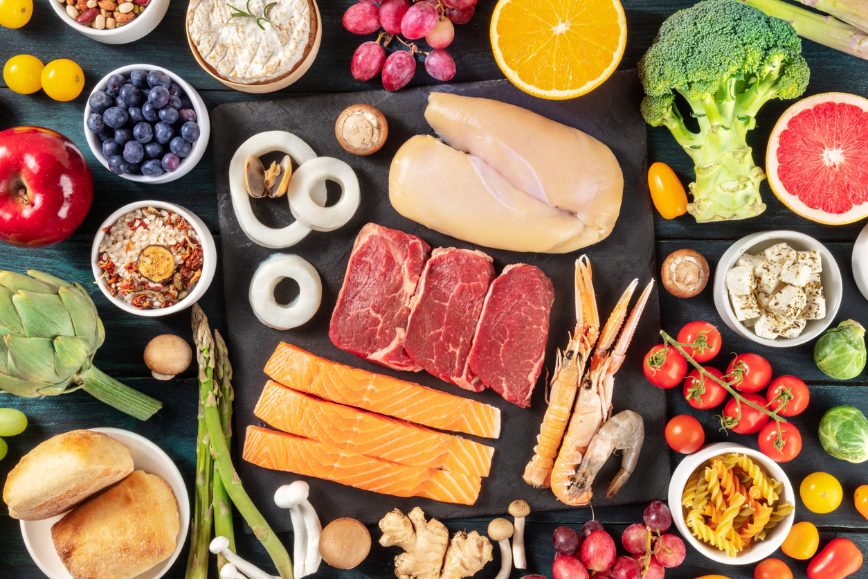 Food, overhead shot. Meat, fish, poultry, seafood, cheese, fruit and vegetables, mushrooms and many other products on a dark background
