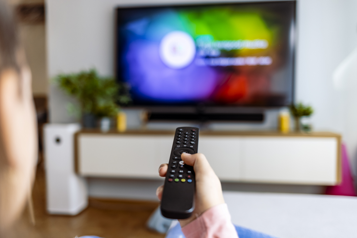 Hand with remote control in front of the tv