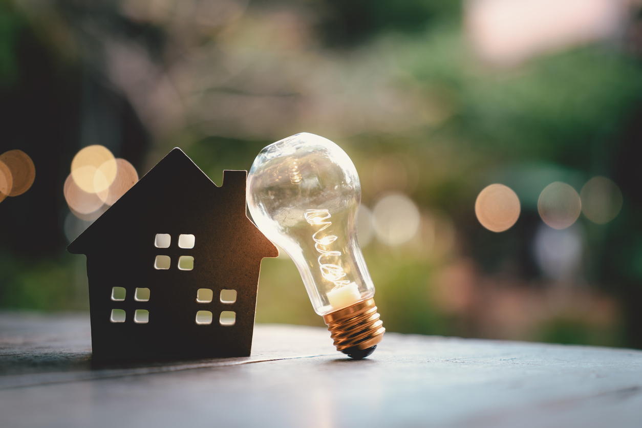 Light bulb with wood house on the table, a symbol for construction, Creative light bulb idea, power energy or business idea concept ecology, loan, mortgage, property or home.