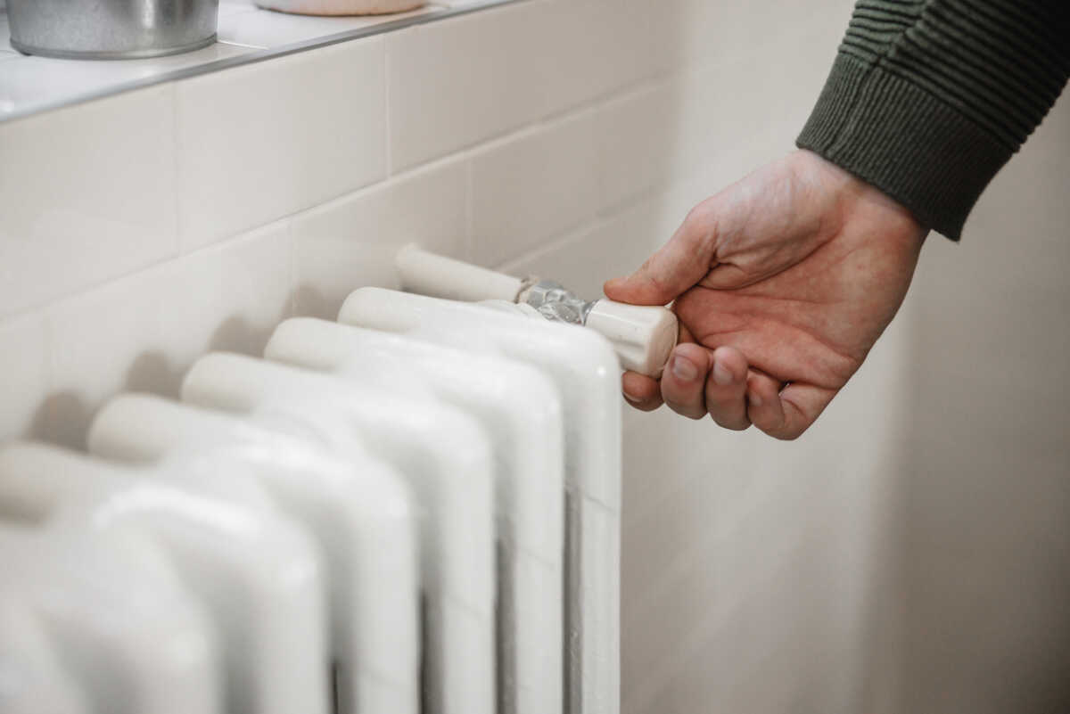 Hand trying to turn the heat on, home heater supply cut off due to gas and oil price escalation, global economic crisis