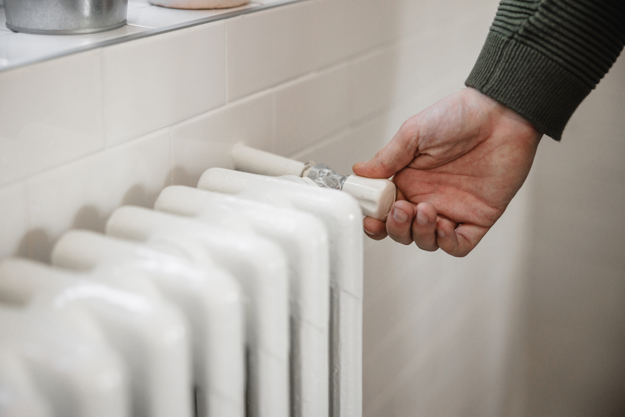 Hand trying to turn the heat on, home heater supply cut off due to gas and oil price escalation, global economic crisis
