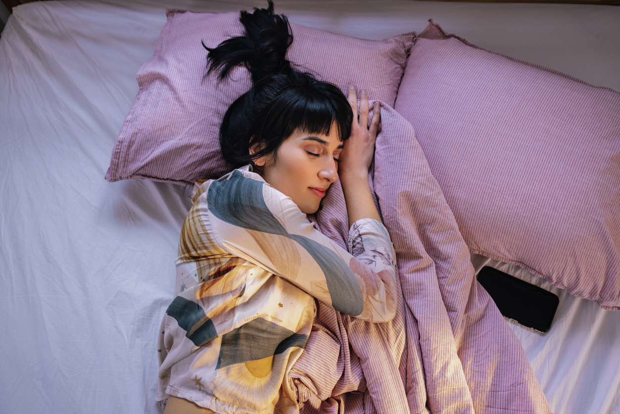 Above shot of a young Caucasian woman lying in her bed, sleeping.