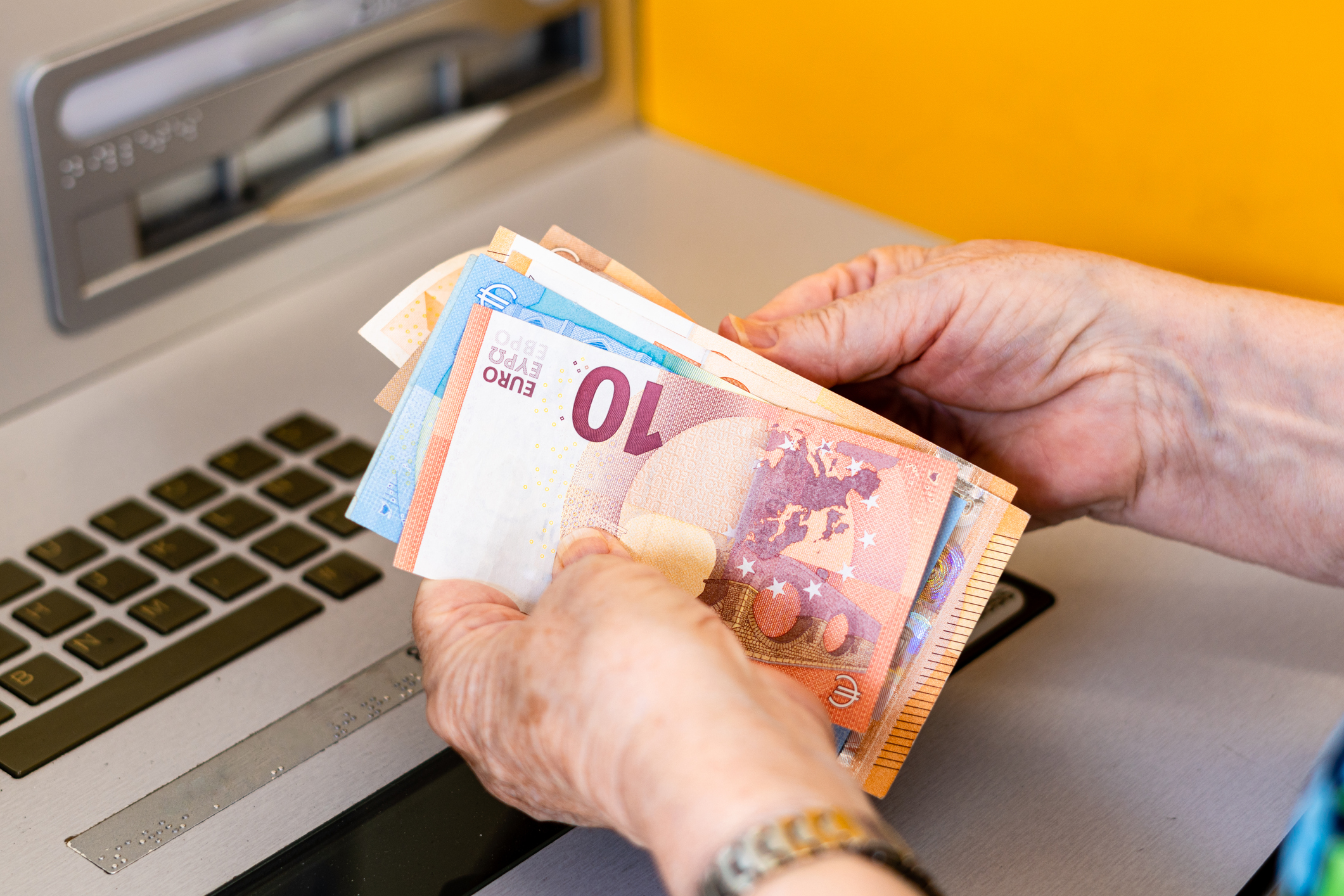 Close-up, woman's hands counting euro bills at the ATM