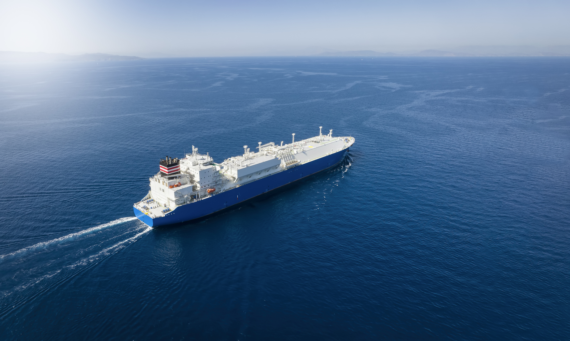 Aerial view of a large LNG or liquid gas tanker ship traveling over blue ocean, with copy space