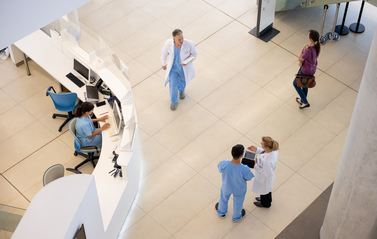 Group of doctors and nurses working at the hospital and walking around the entrance hall - healthcare and medicine concepts
