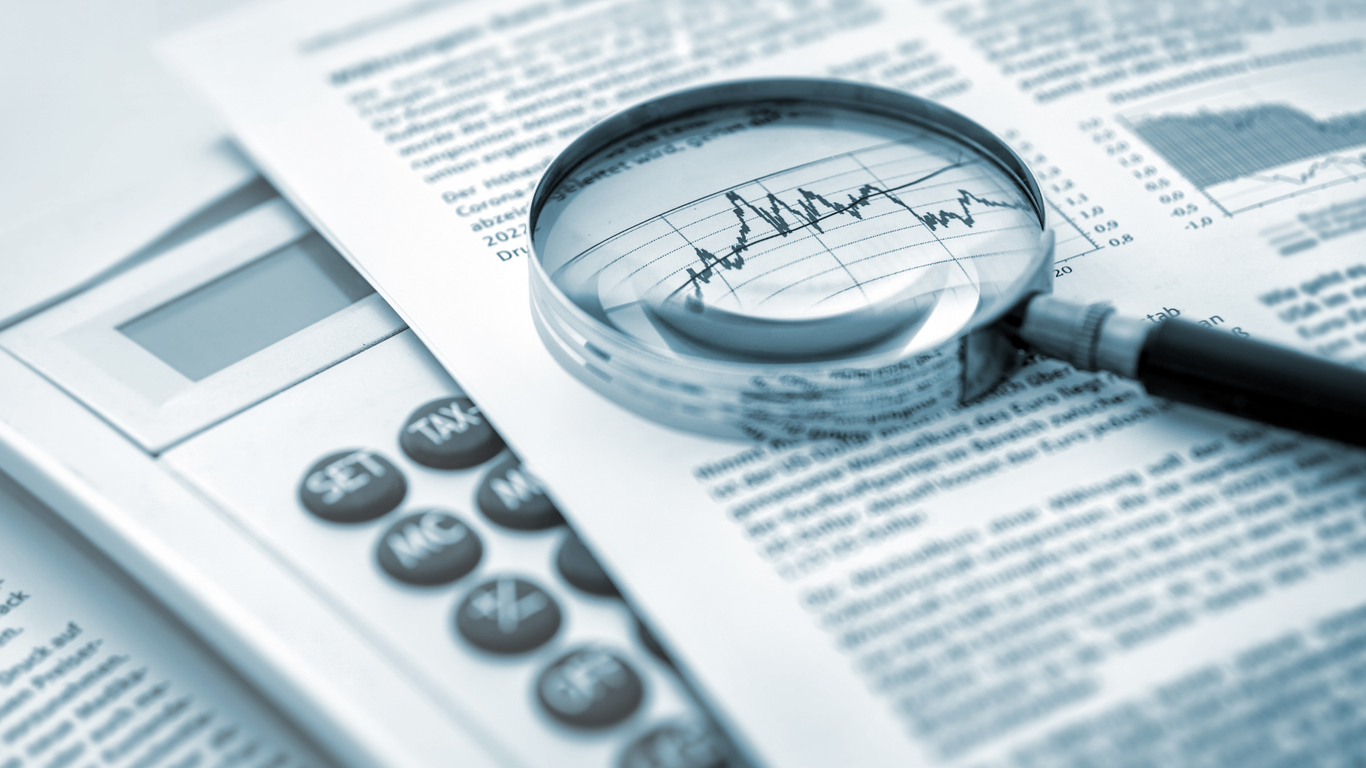 Magnifying glass, calculator and charts on paper symbolizing business and financial market. Blue toned image. studio shot in raw format taken with prime lens for best quality