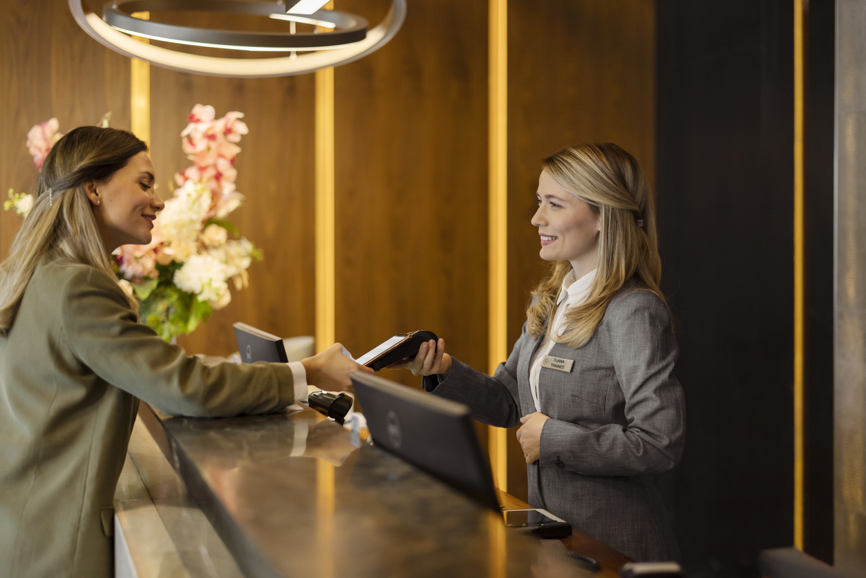 Woman paying with credit card at hotel reception during check-out