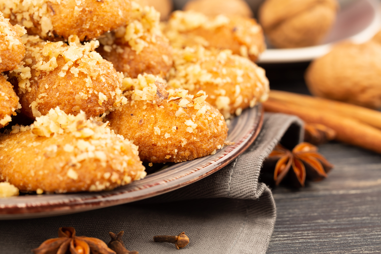 Greek and Cyprus traditional Christmas sweets Melomakarona, cinnamon sticks, walnuts and anise stars on wooden background. Honey cookies.