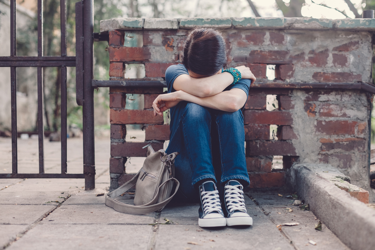 Crying girl with head in hands sitting on the ground