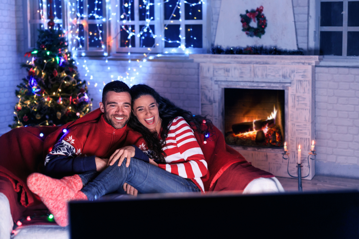 Young couple resting at home and watching TV in front of fireplace.