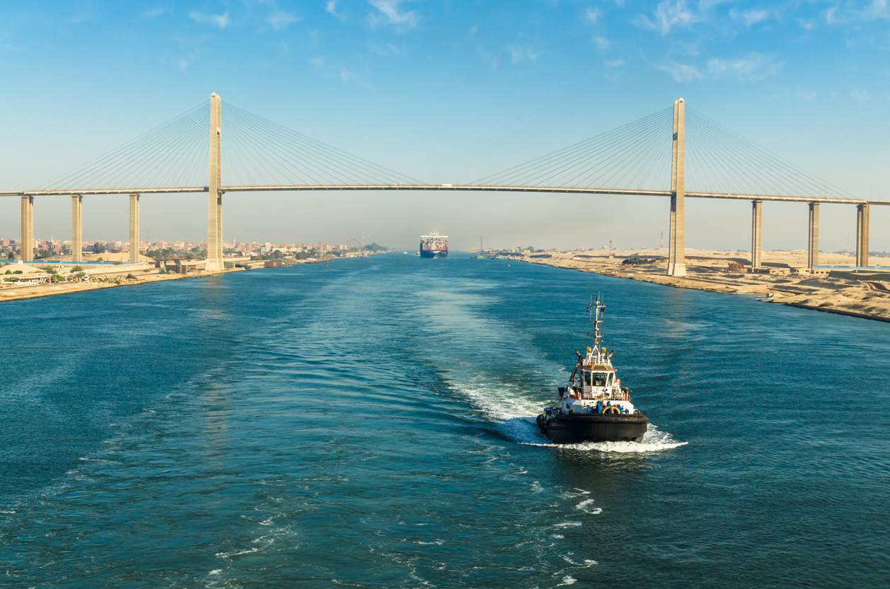 Ship's  convoy with cargo vessel container ship passing through Suez Canal, in the background - the Suez Canal Bridge, also known as Al Salam Bridge, Suez Canal, Egypt
