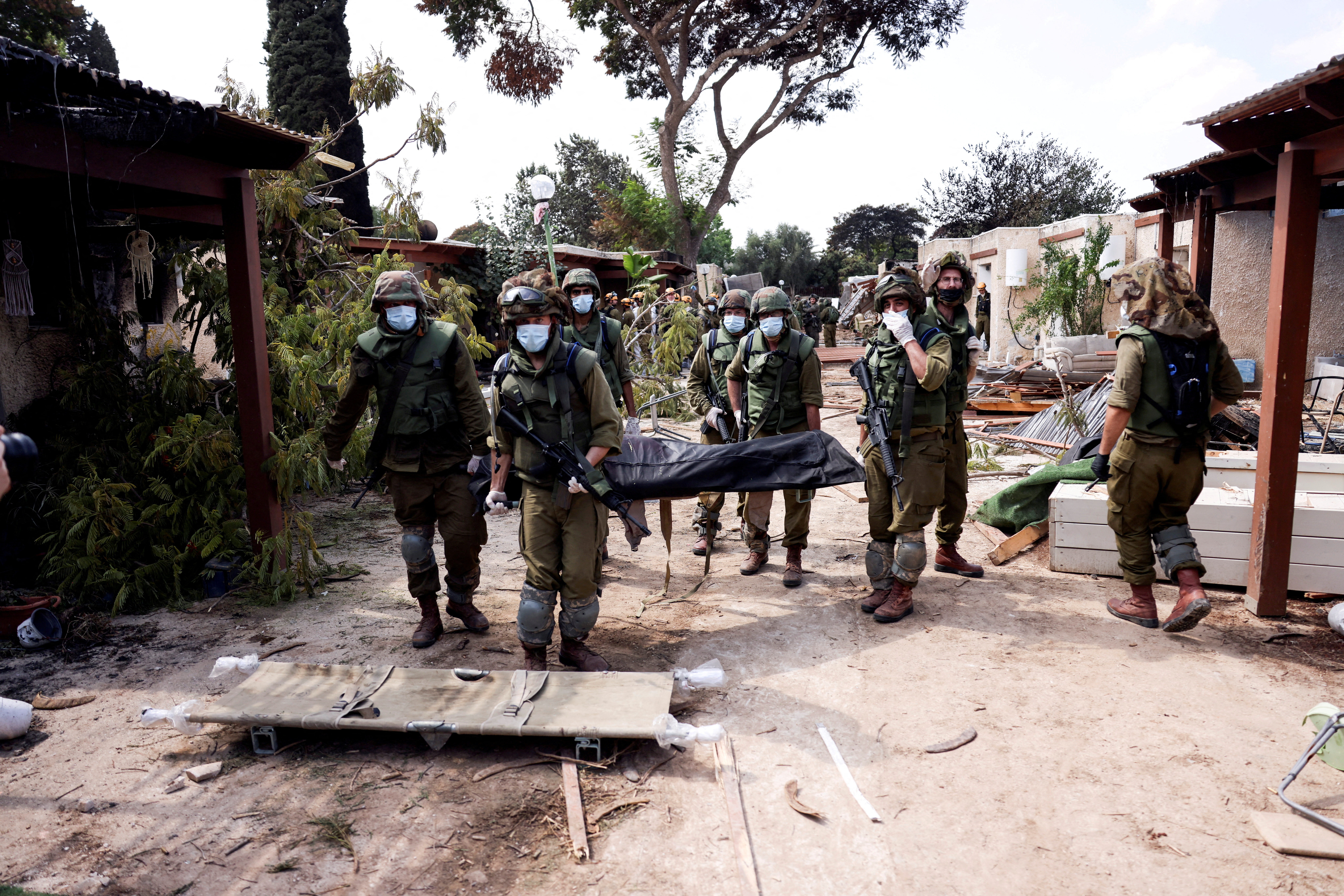 FILE PHOTO: Israeli soldiers carry the body of a victim of an attack by militants from Gaza at Kibbutz Kfar Aza, in southern Israel, October 10, 2023. REUTERS