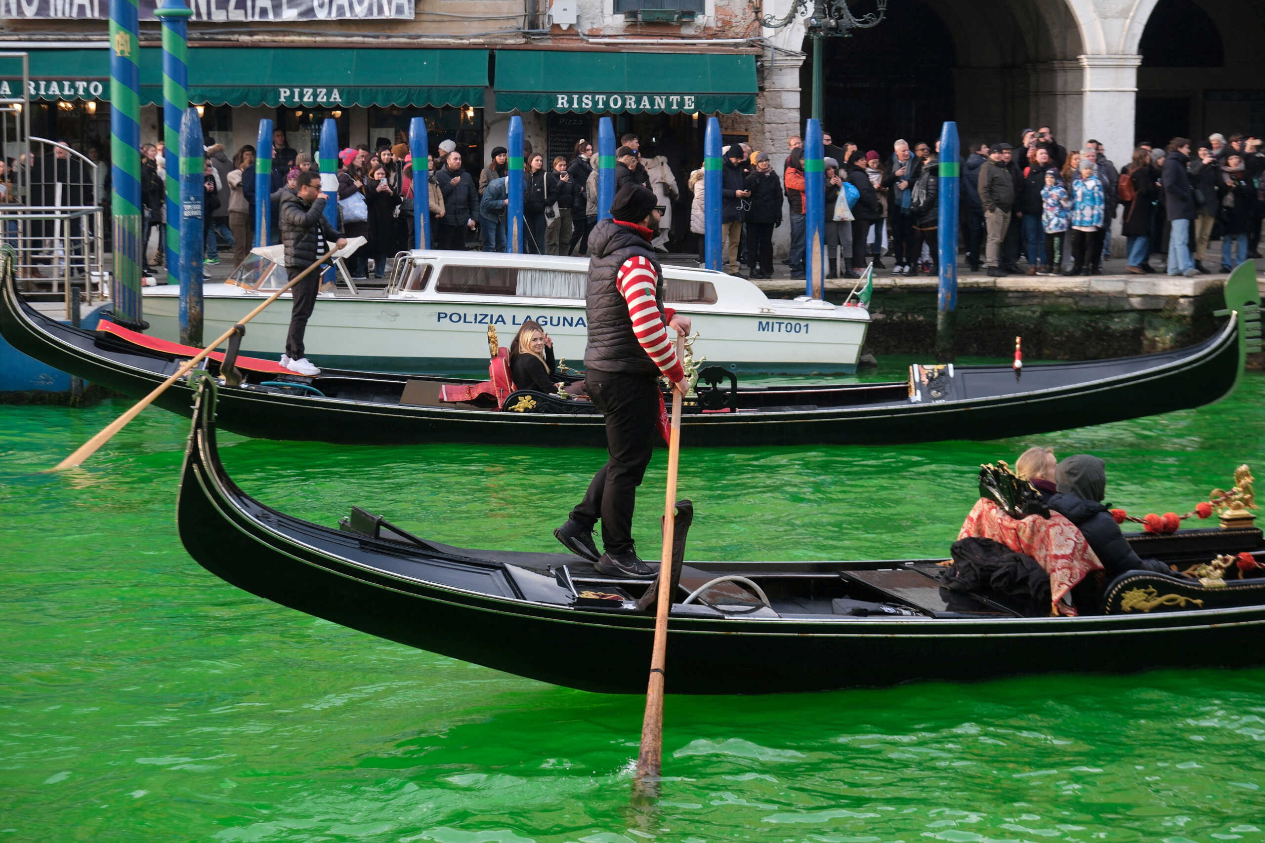 People ride in boats as waters of Grand Canal turned green after a protest by 'Extinction Rebellion' climate activists in Venice, Italy, December 9, 2023. REUTERS